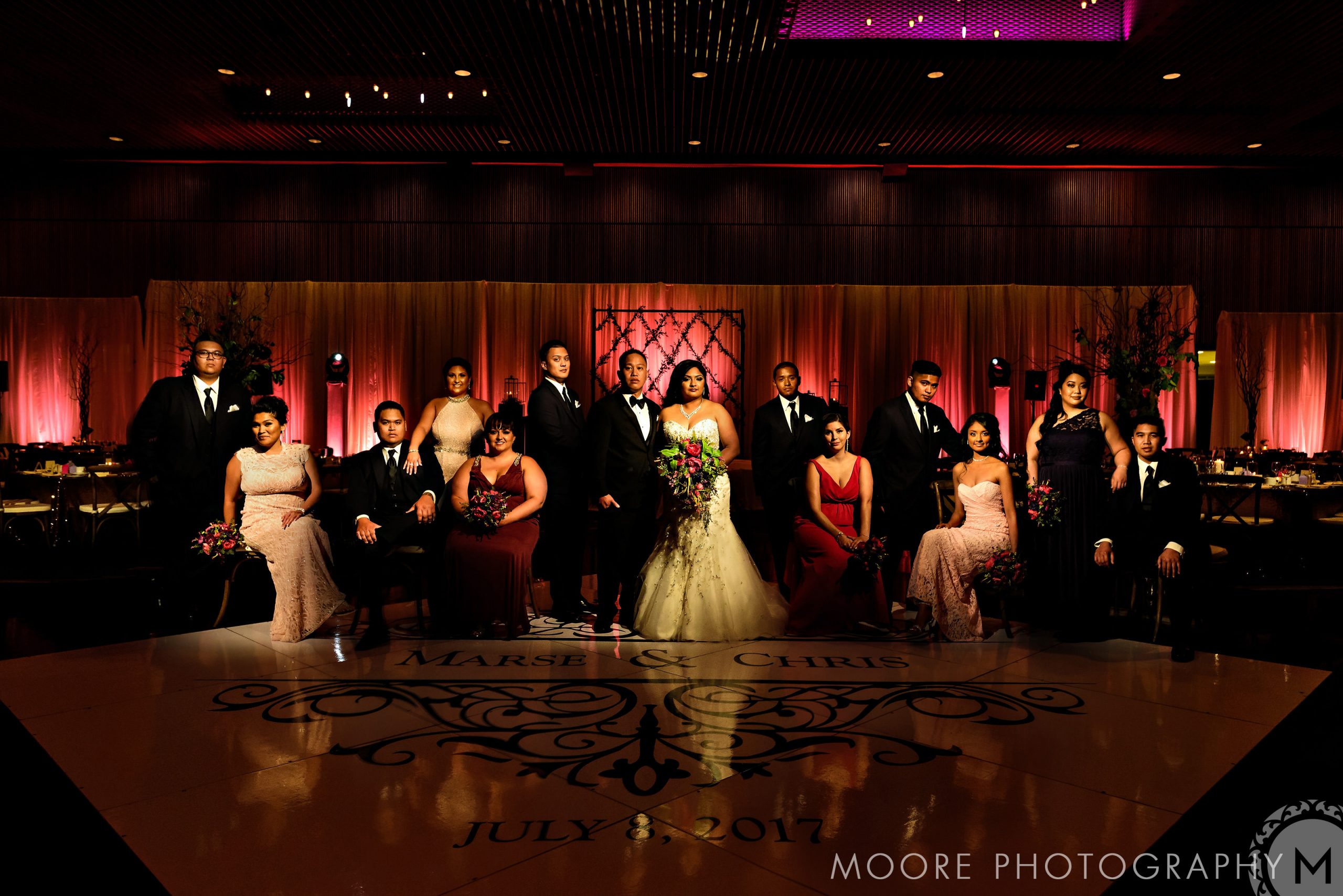 A Winnipeg wedding party poses elegantly in formal attire on a decorated stage.