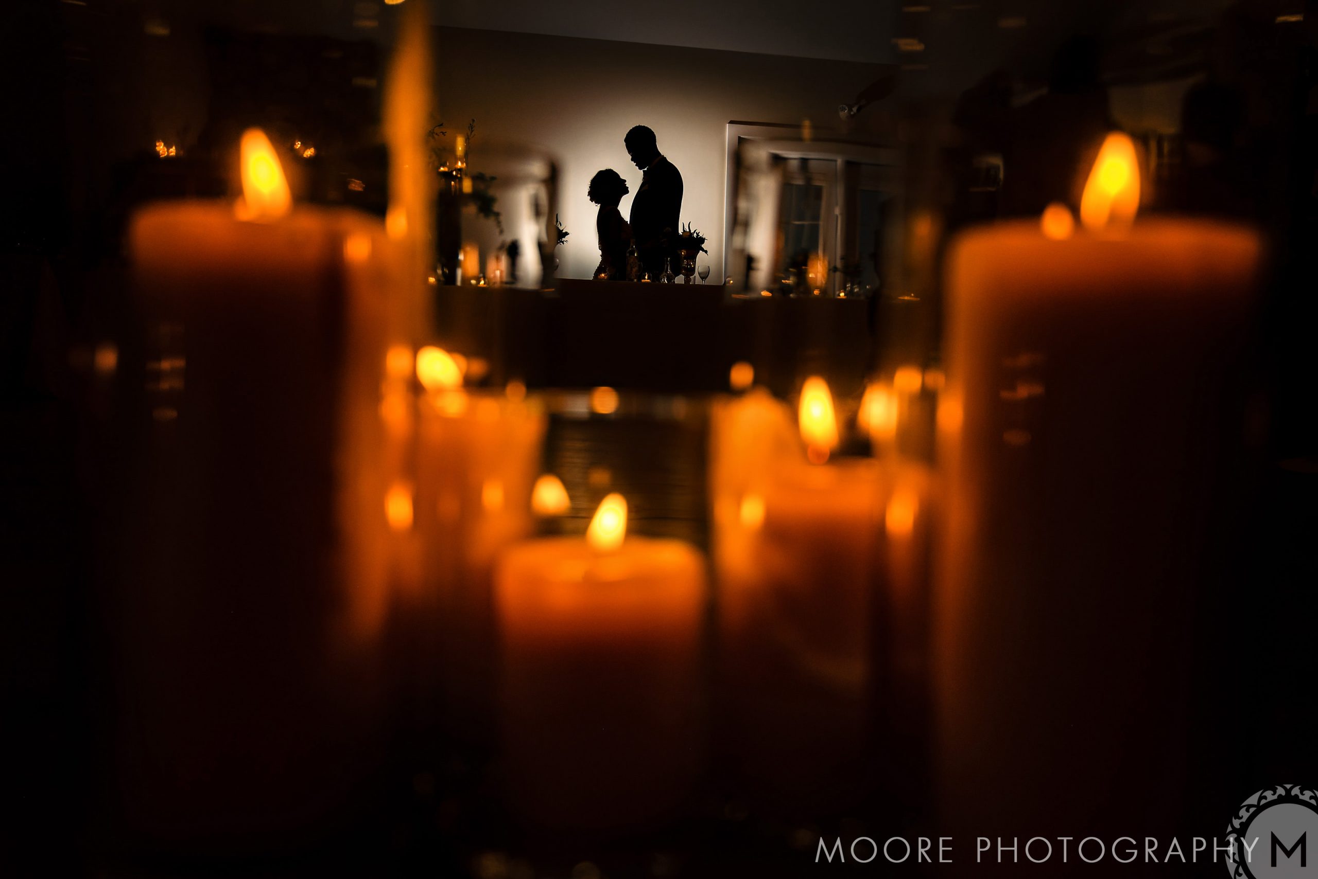 Silhouetted couple in a dim room, glowing candles; Winnipeg wedding venue ambiance.