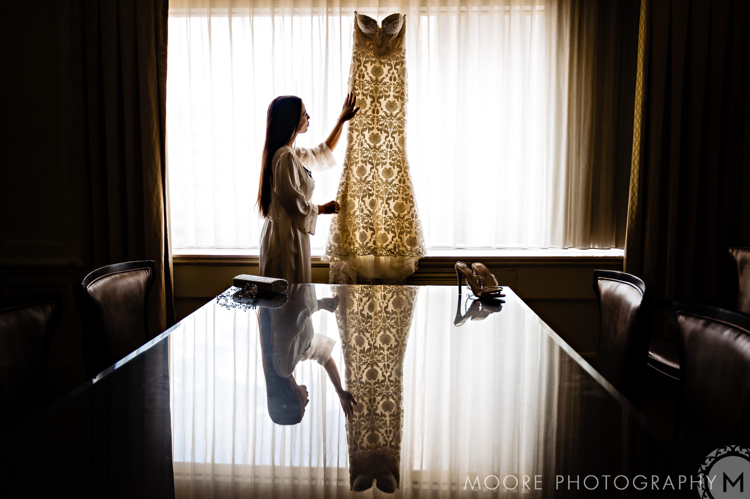 Woman admiring lace dress in well-lit room, dreaming of Winnipeg wedding venues.