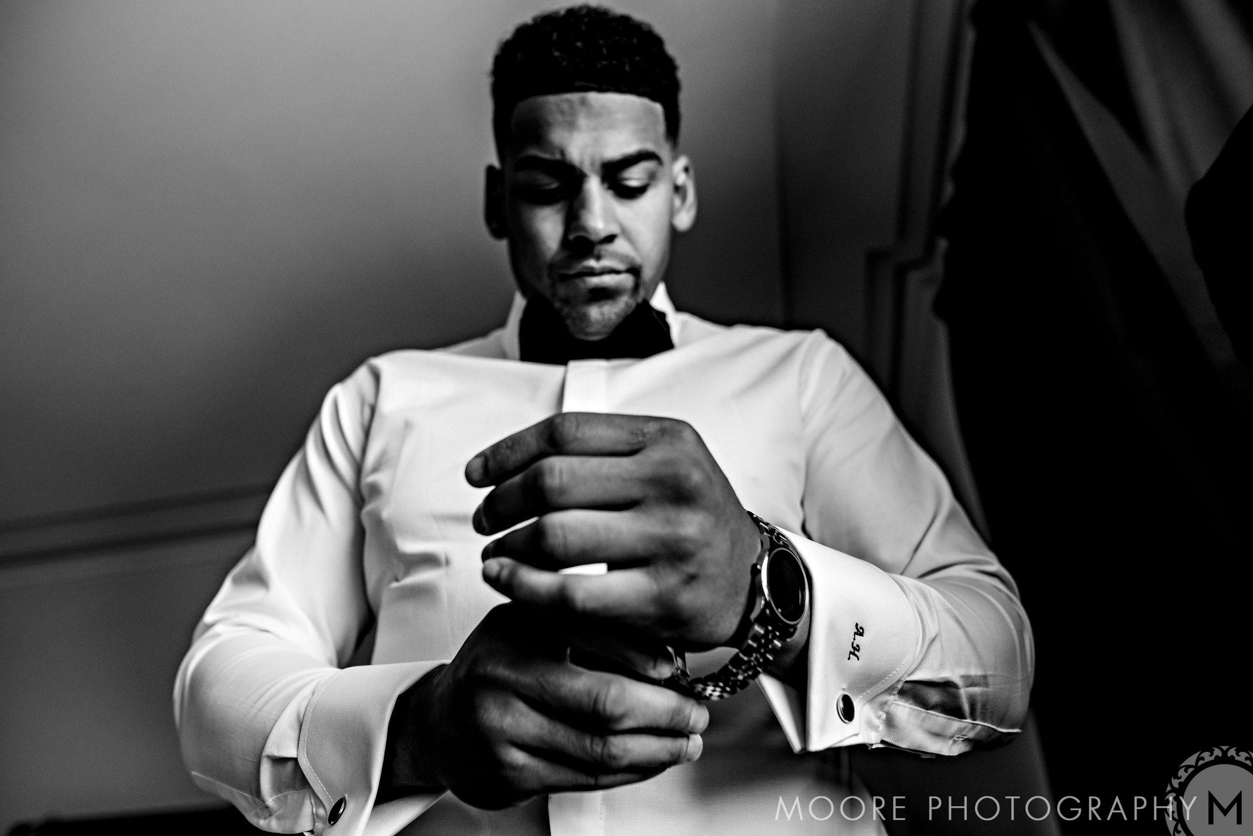 Andrew Harris in formal attire adjusting cuffs, viewed from below. Black and white photo.