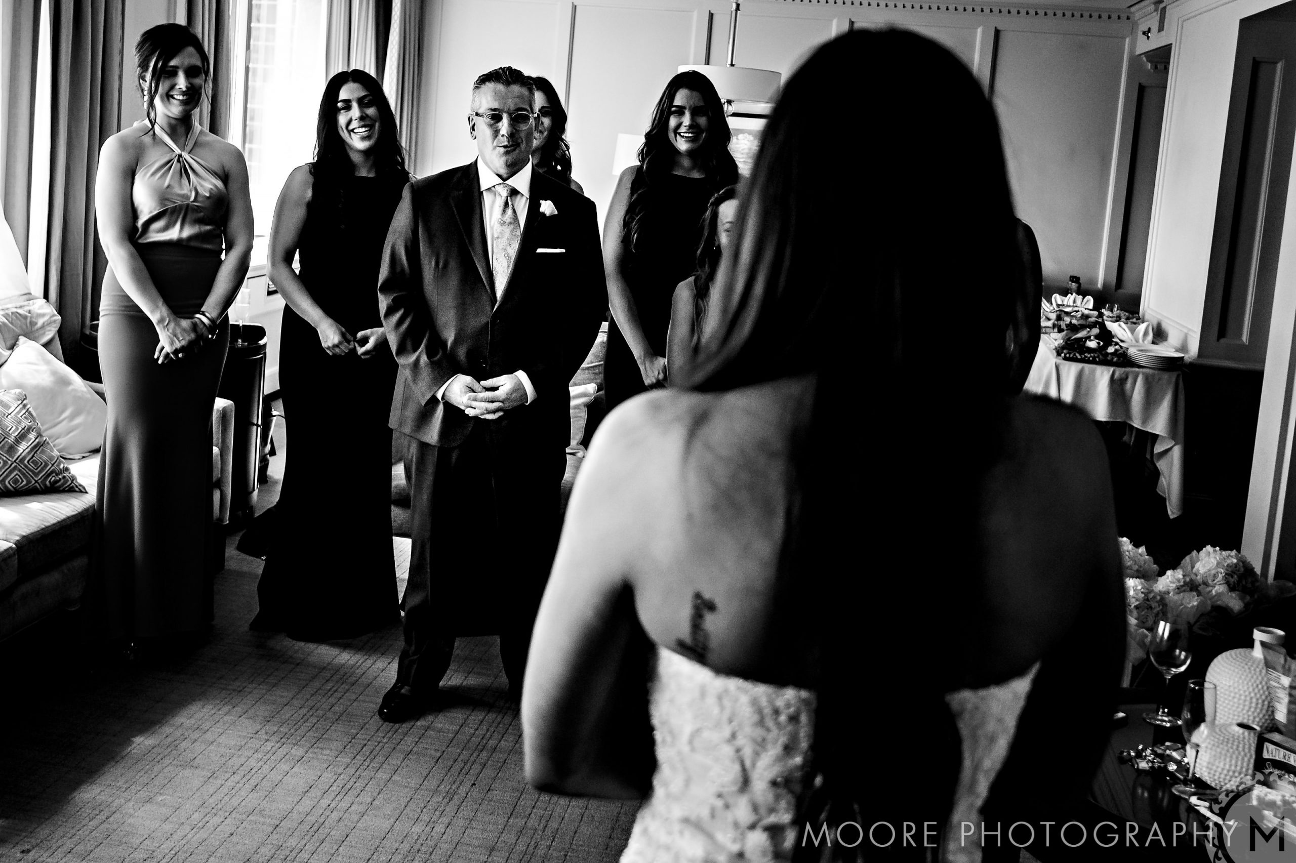 Bride facing family in a room, all warmly smiling, for the Andrew Harris wedding.