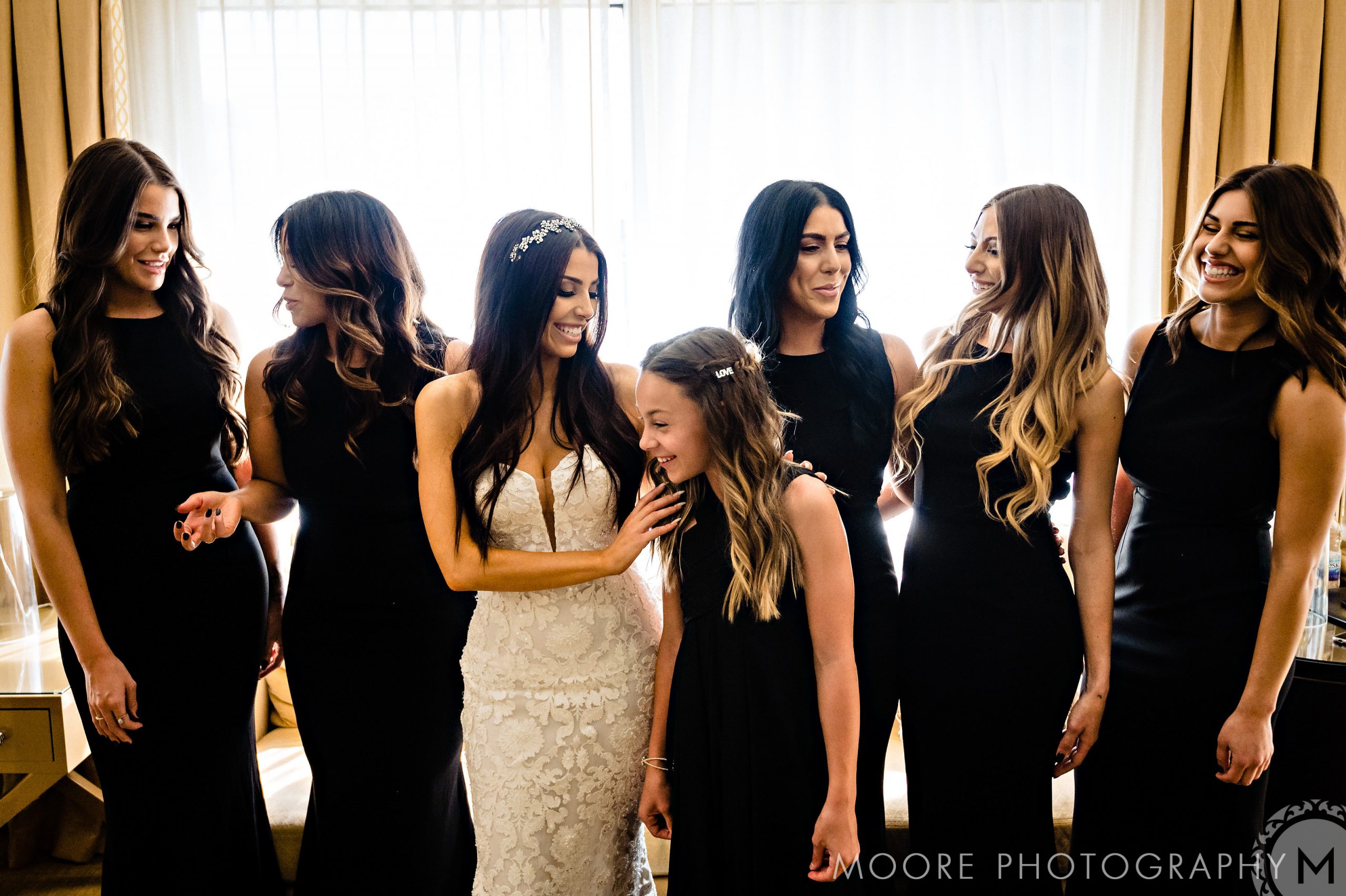 Bride and bridesmaids in black dresses enjoy a joyful moment at the Andrew Harris wedding.