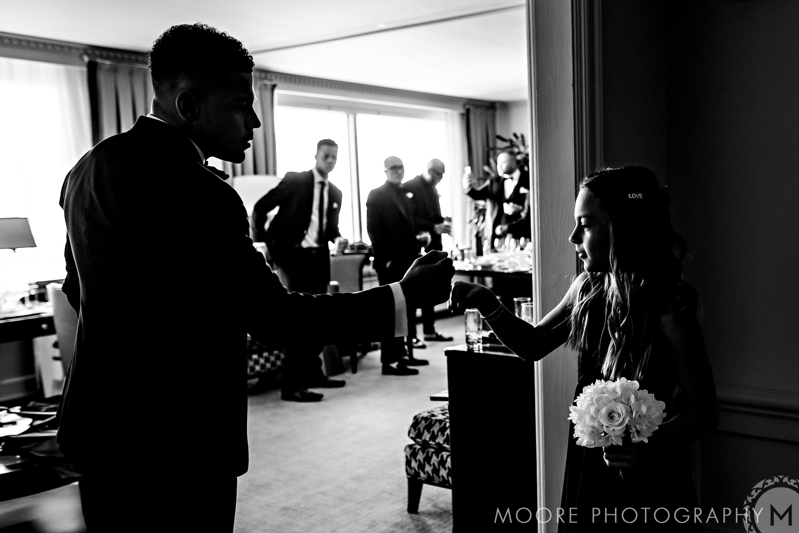 Man and girl fist bump at Andrew Harris's wedding; she holds a bouquet.