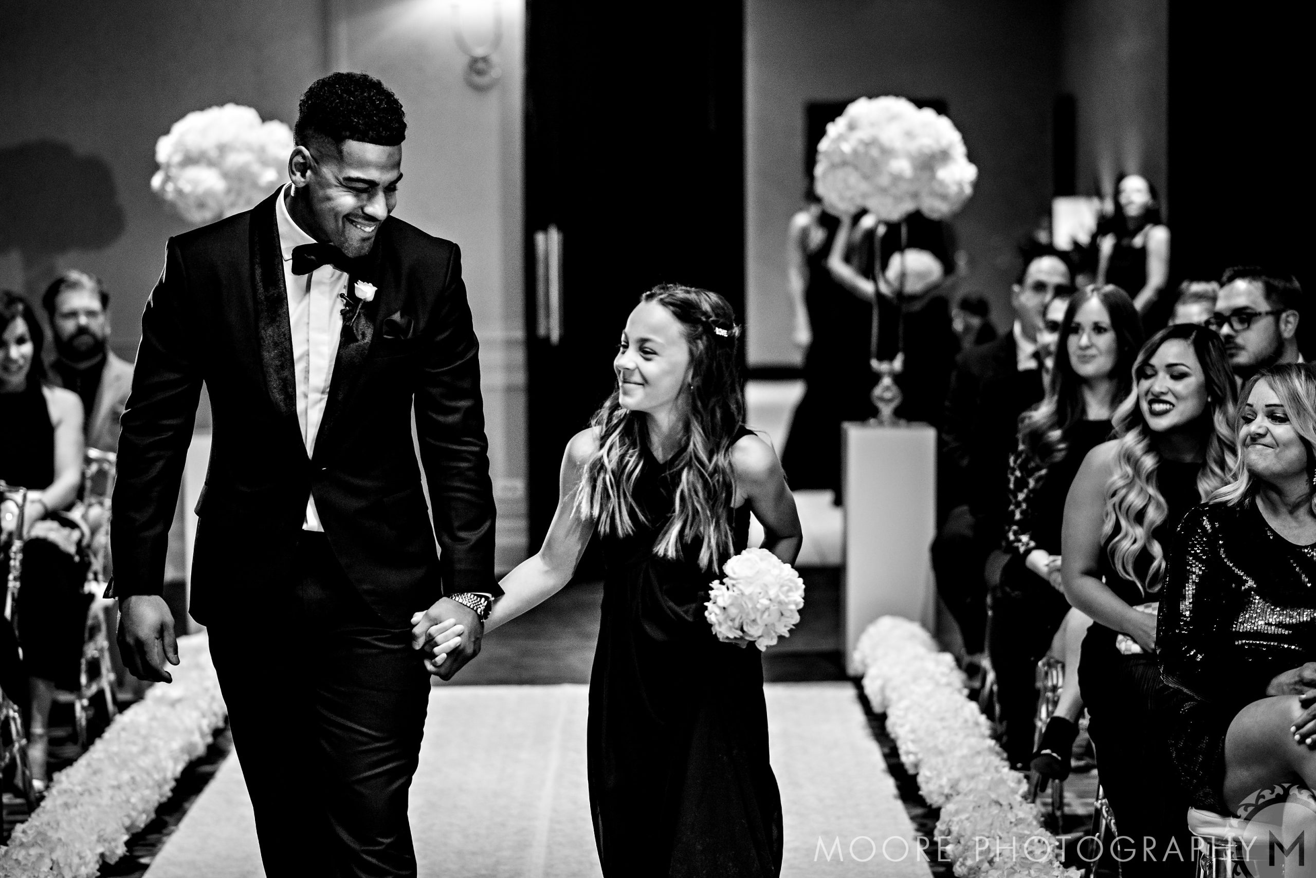 Man and woman smiling, holding hands at Andrew Harris's wedding.