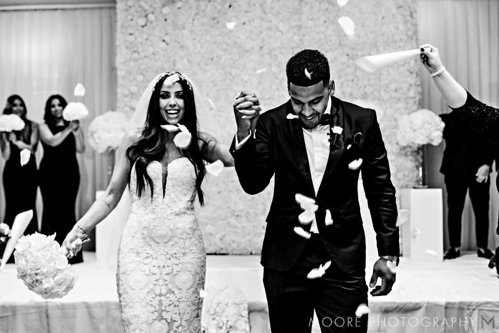 Bride and groom at Andrew Harris wedding, hand in hand as petals fall around them.