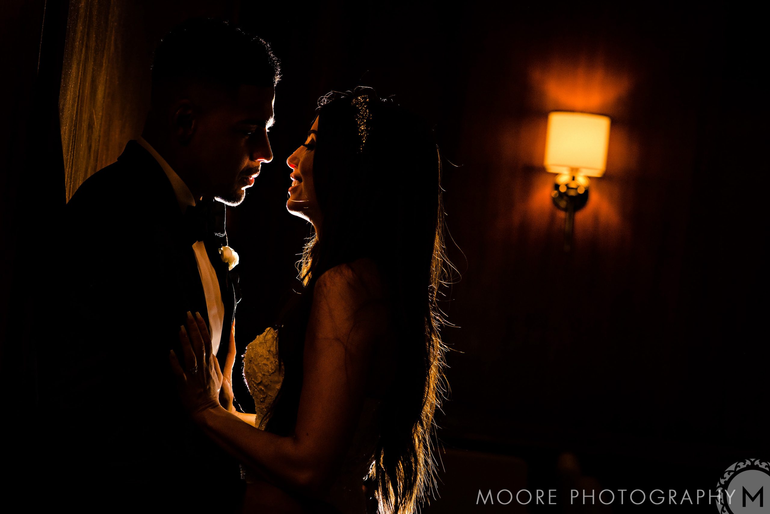 Andrew Harris Wedding. Silhouetted couple embracing in dramatic lighting at an Andrew Harris wedding.