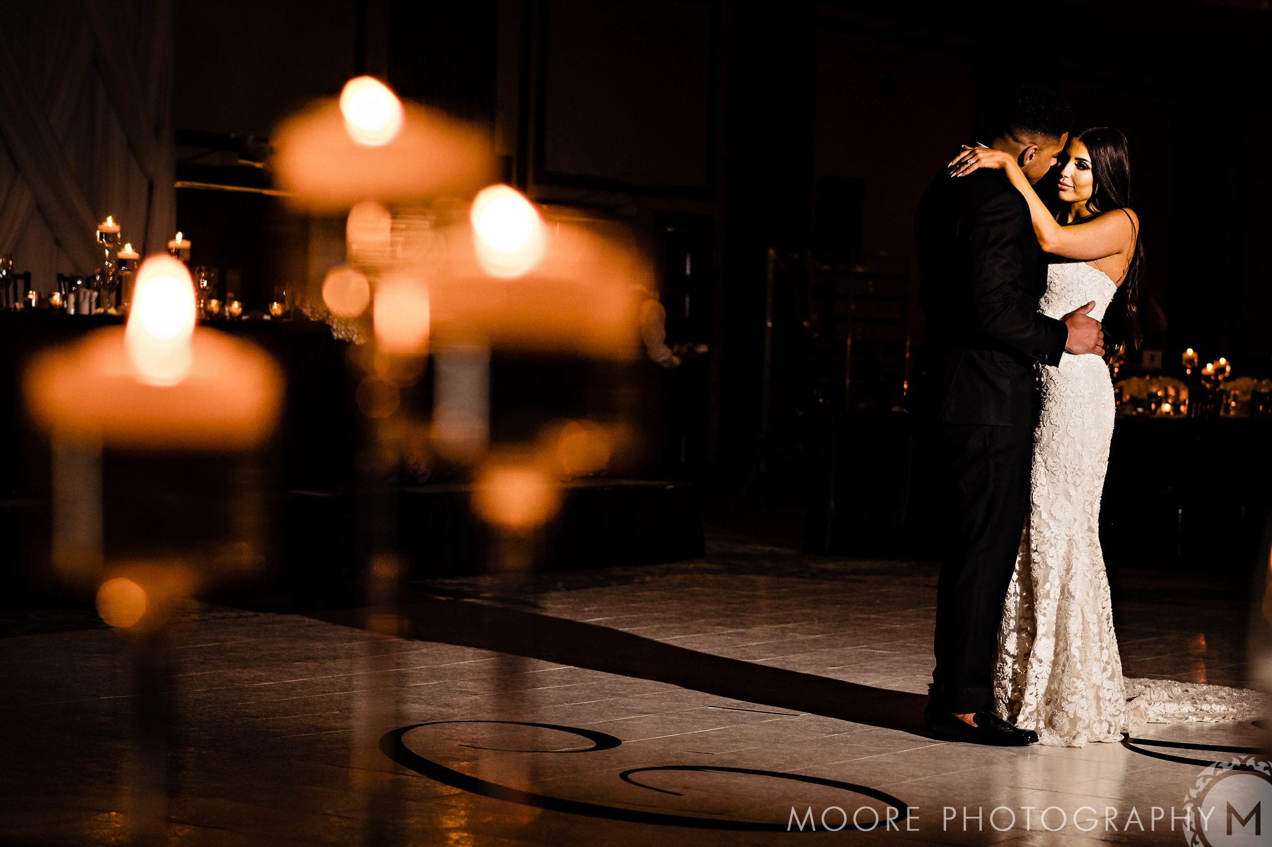Couple dances romantically in dim room, glowing candles set for Andrew Harris's wedding.