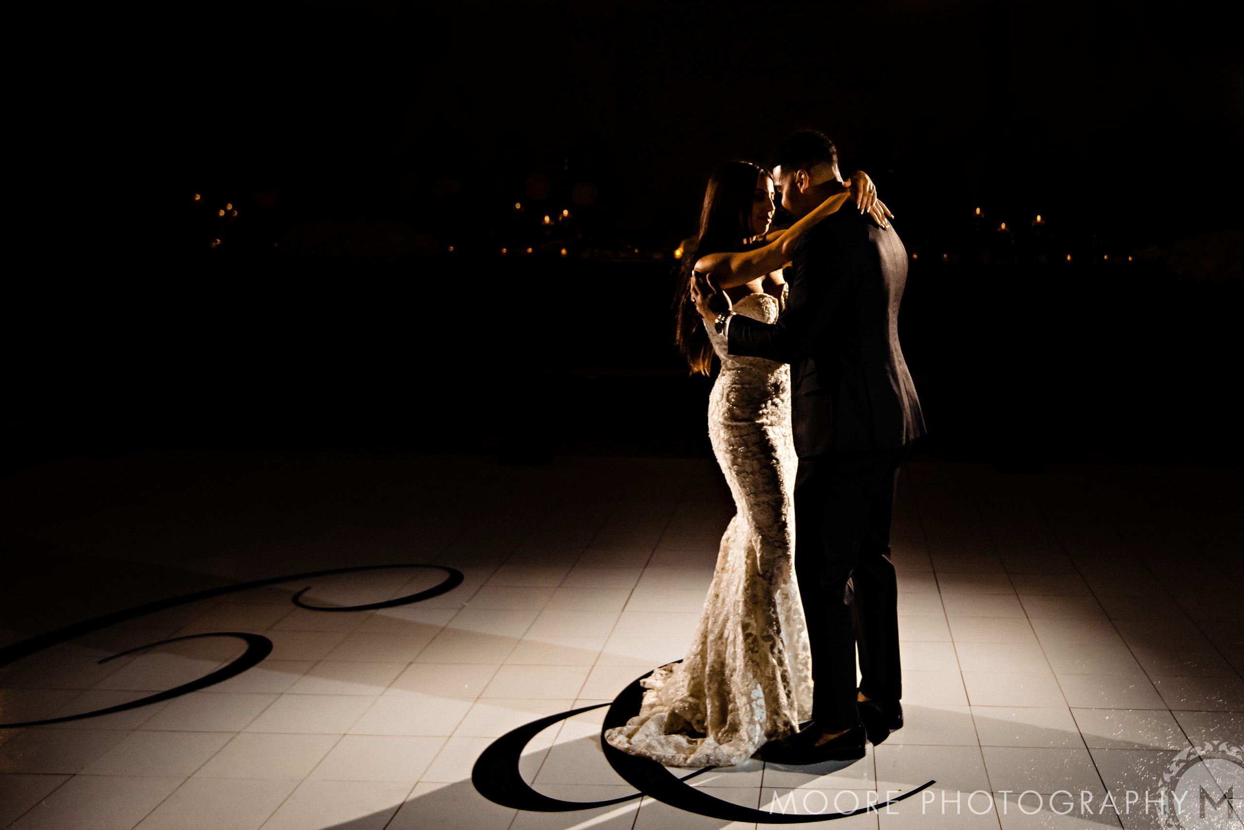 Andrew Harris wedding: A couple dances under a spotlight on a beautifully decorated floor.
