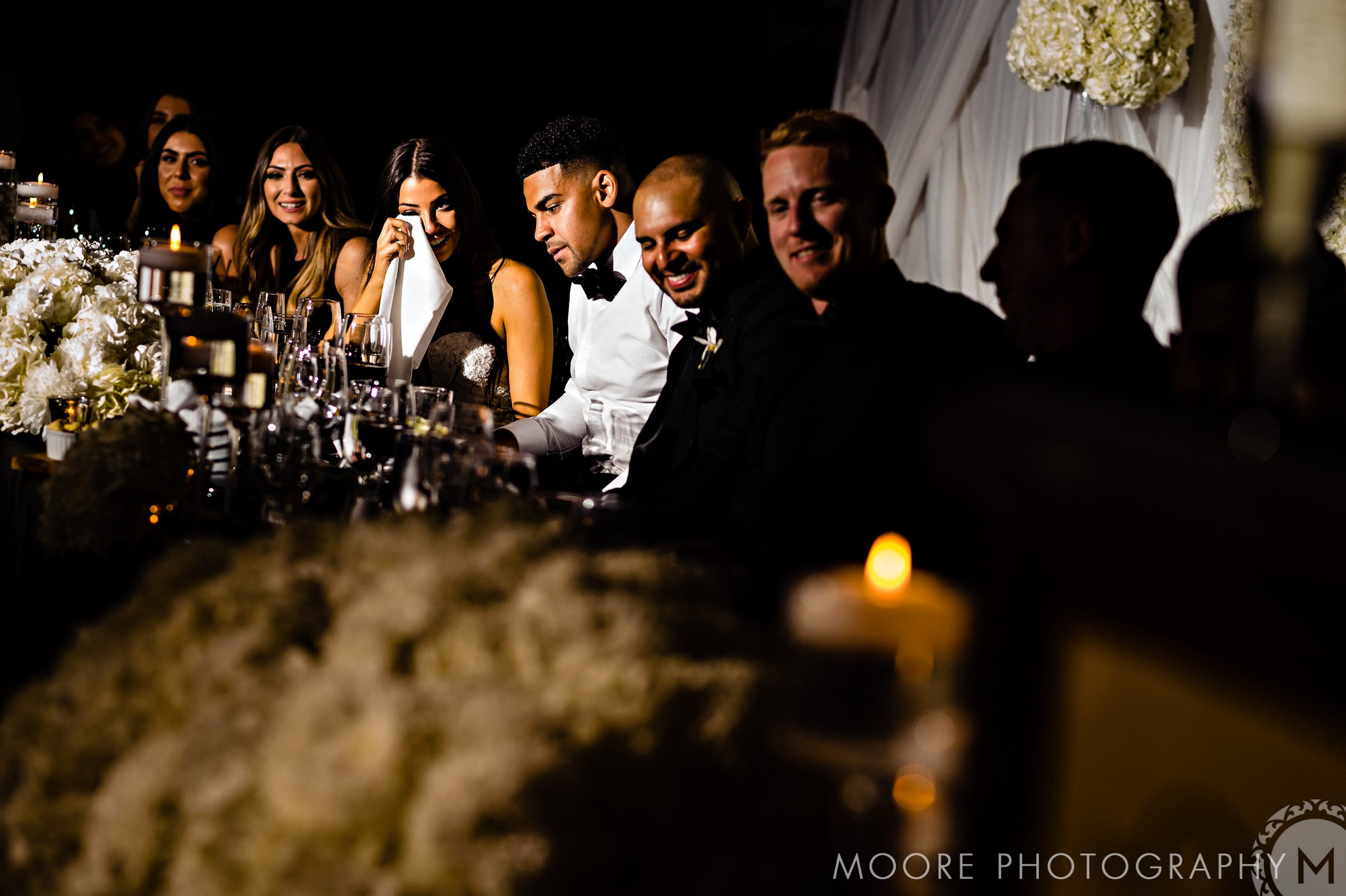 Wedding party at Andrew Harris wedding, woman dabbing tears, others smiling and chatting.