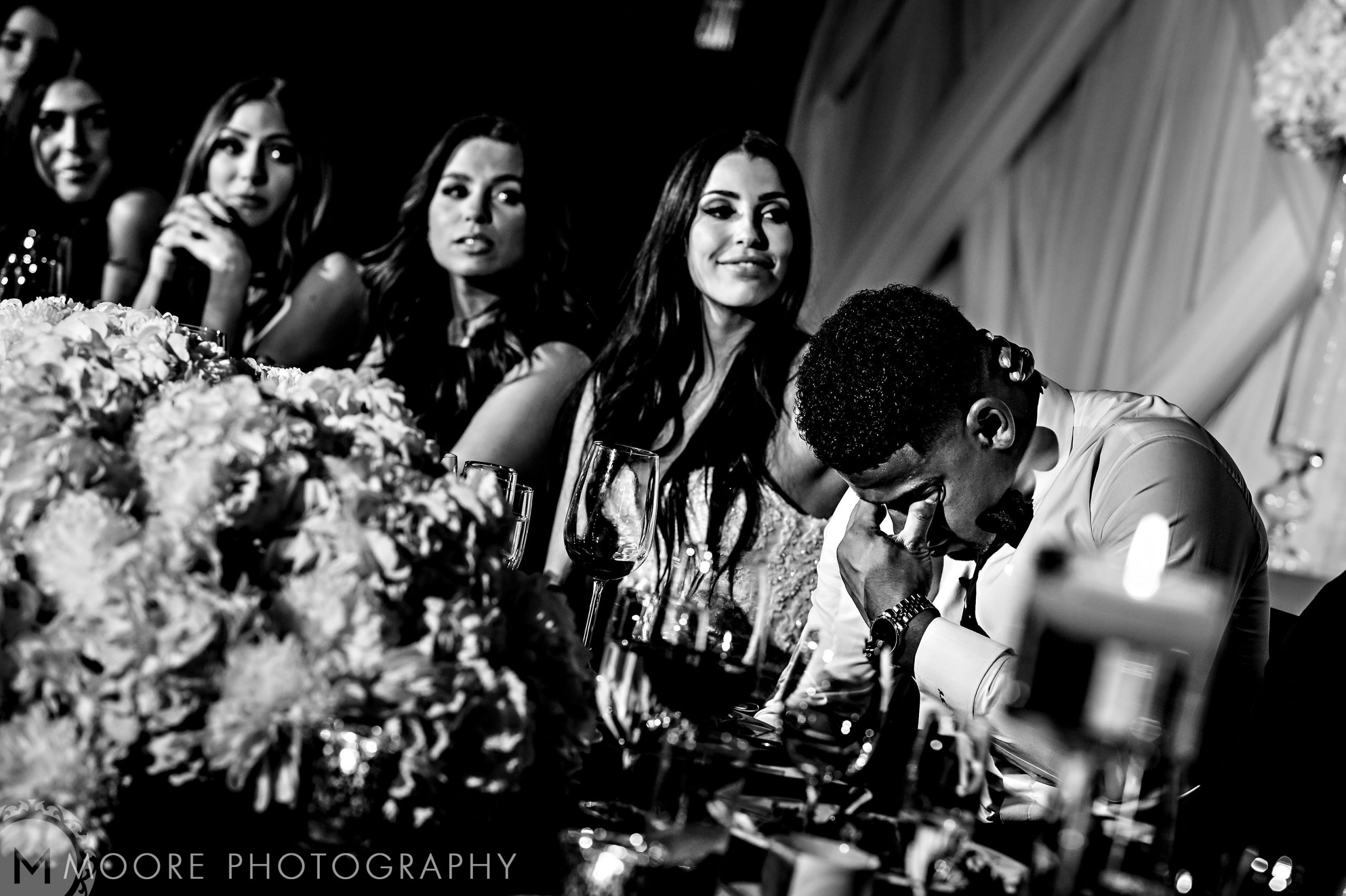 Andrew Harris laughs at a table with people, surrounded by wedding flowers.