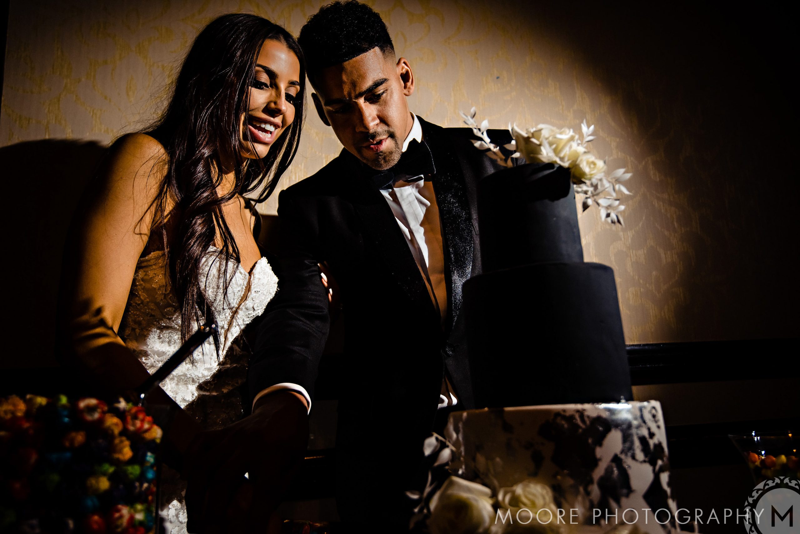Bride and groom cutting a tiered black wedding cake at the Andrew Harris wedding.
