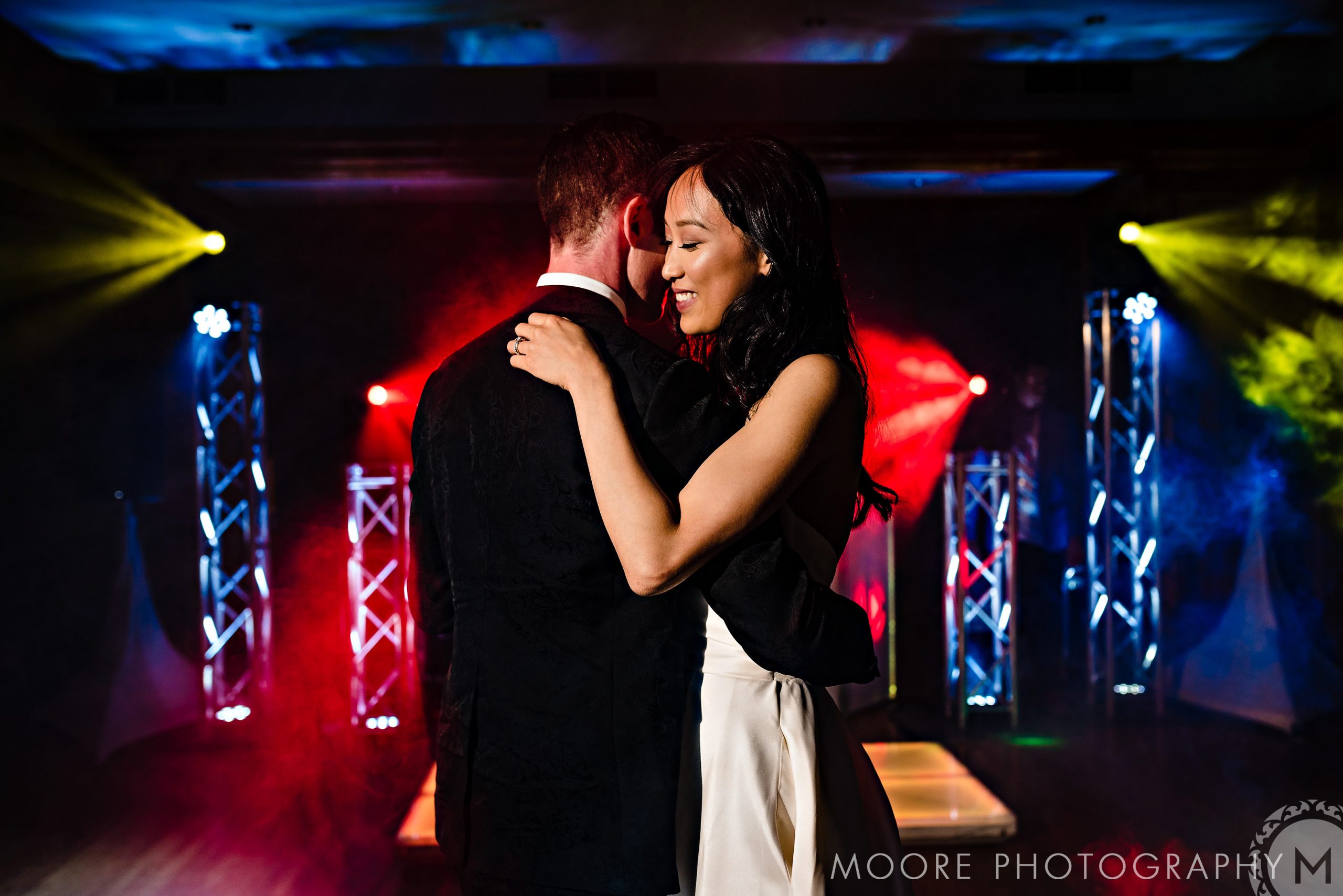 A couple dancing under colorful lights at a Winnipeg wedding venue.