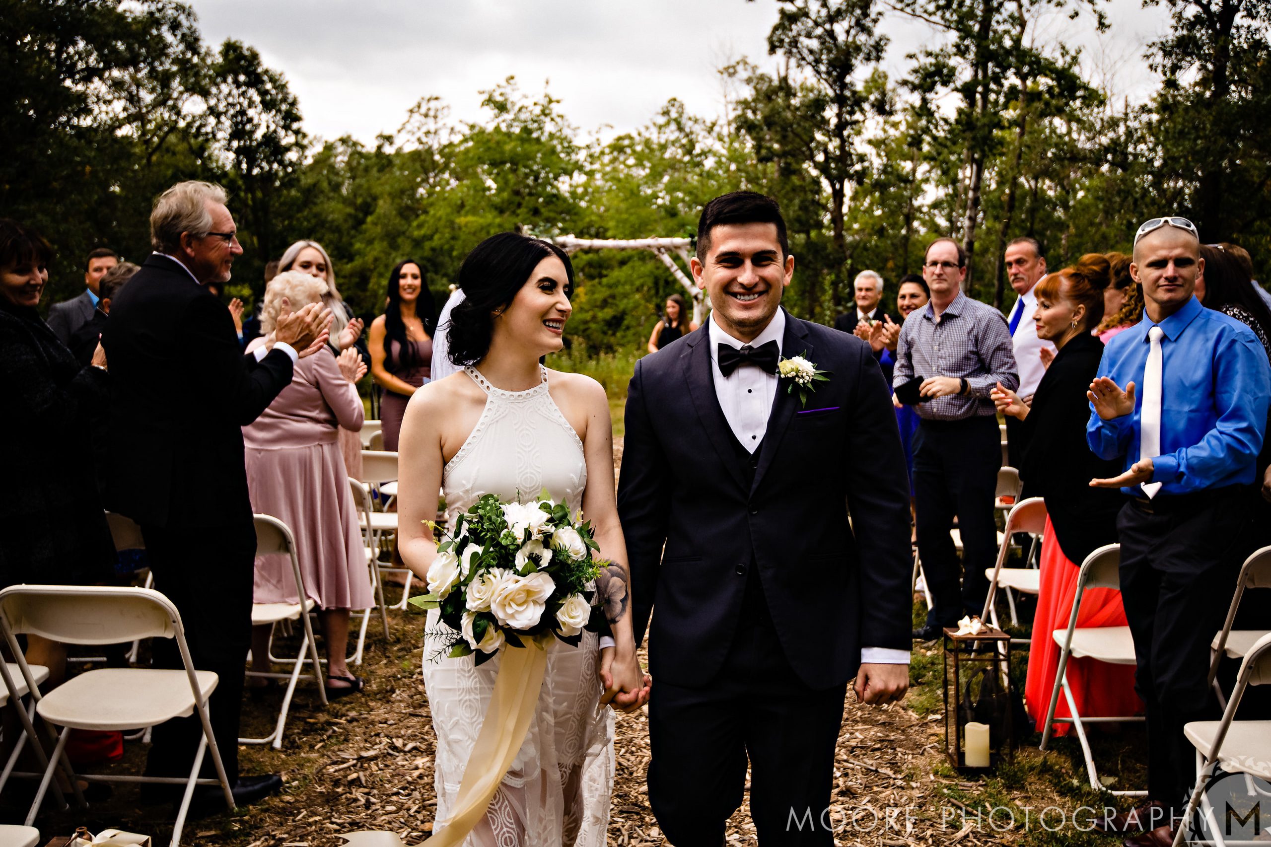 Bride and groom walk down the aisle, smiling at their Winnipeg wedding venue.
