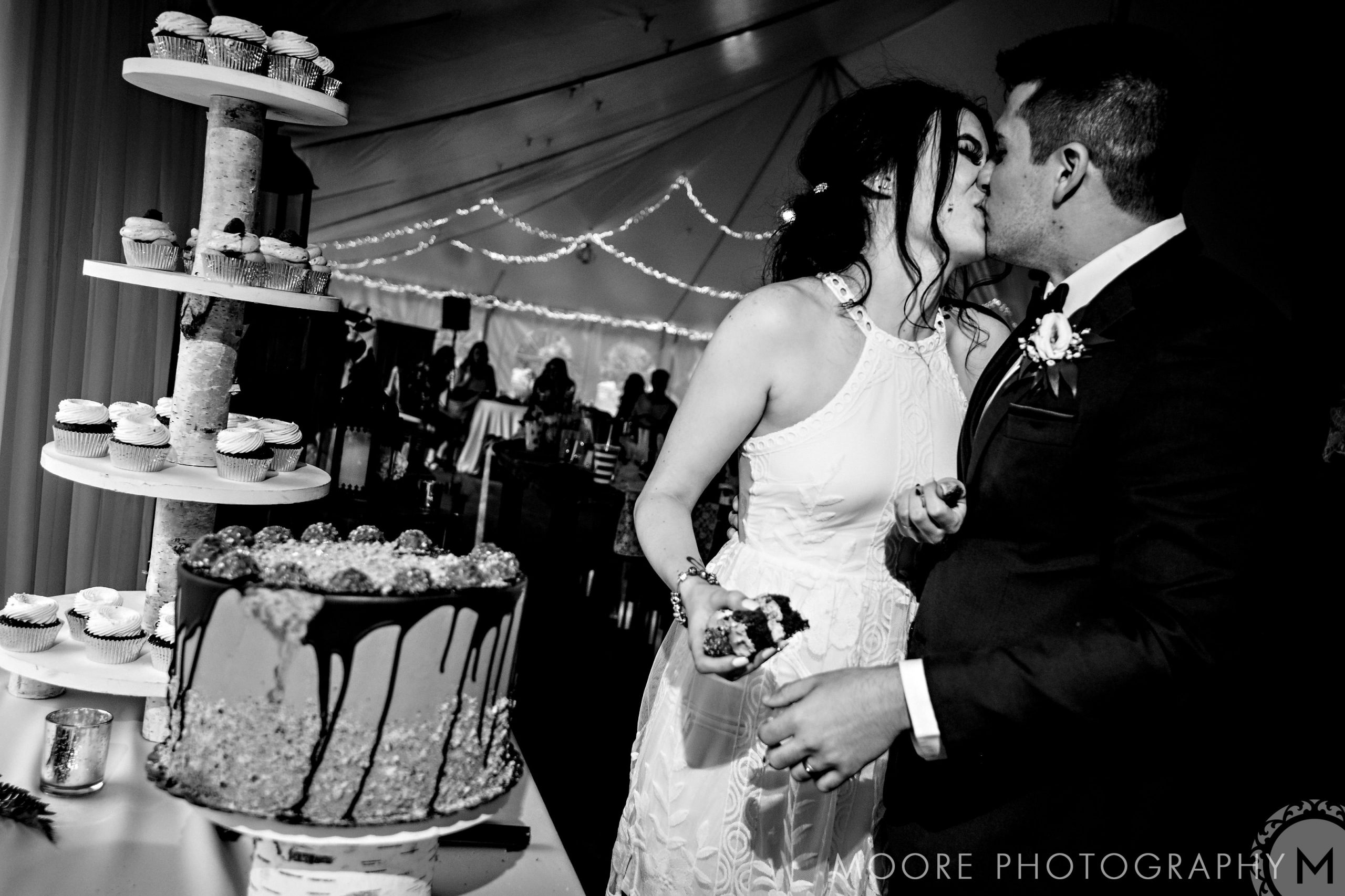 Bride and groom kiss near cake tower in a decorated Winnipeg wedding venue.