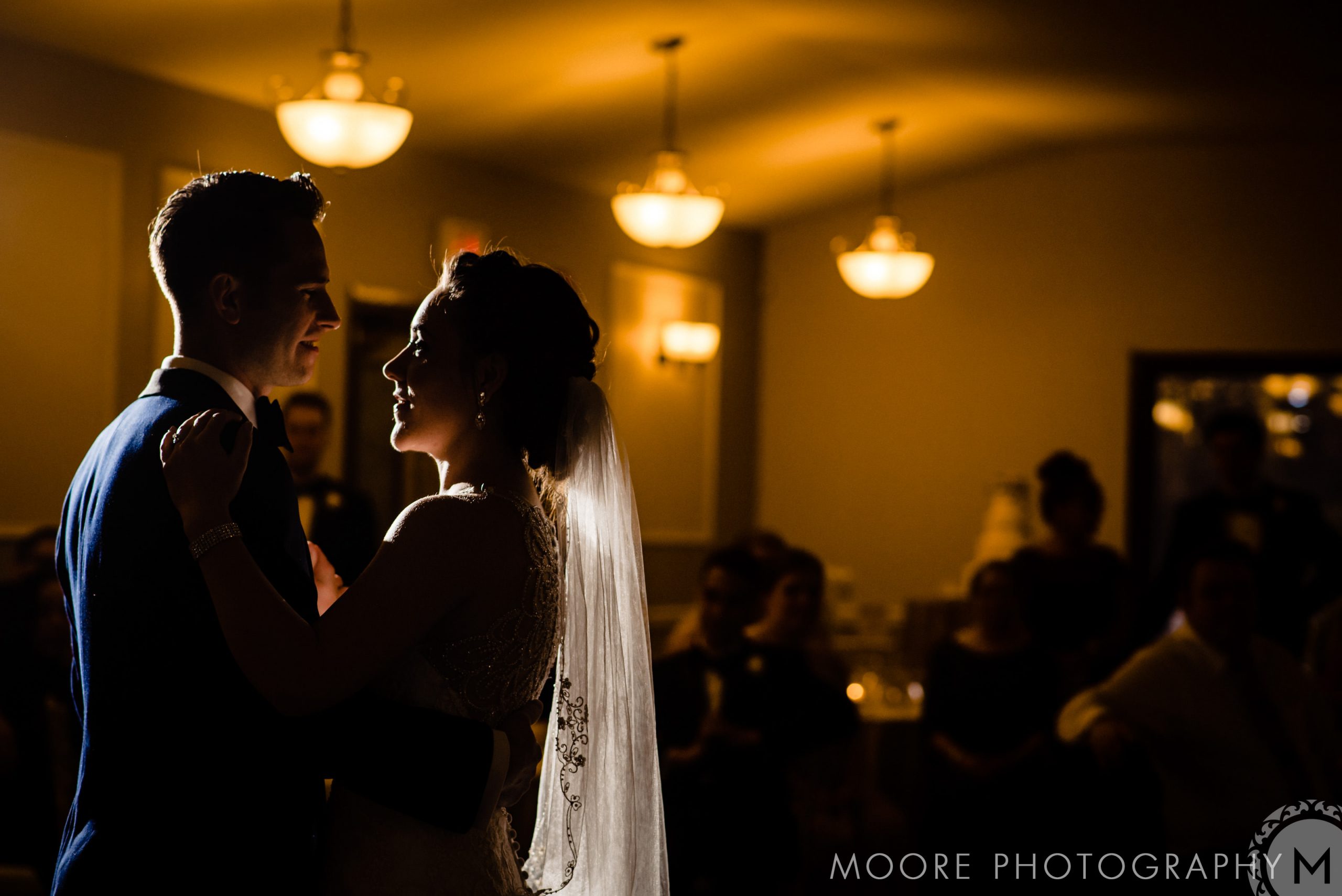 Couple shares a first dance in dimly lit Winnipeg venue; warm lighting highlights them.