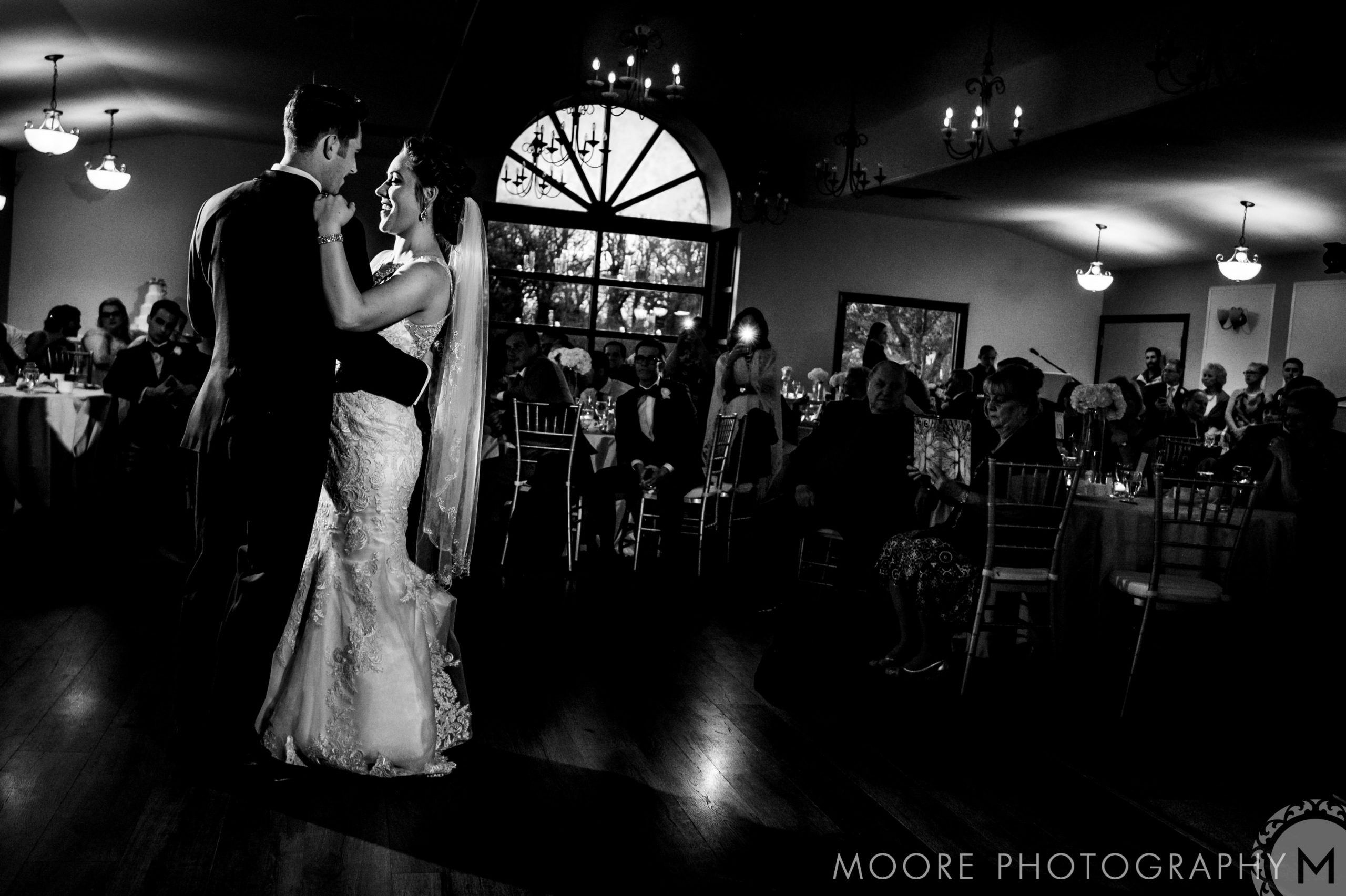 A couple shares a dance at their Winnipeg wedding venue, guests seated around.