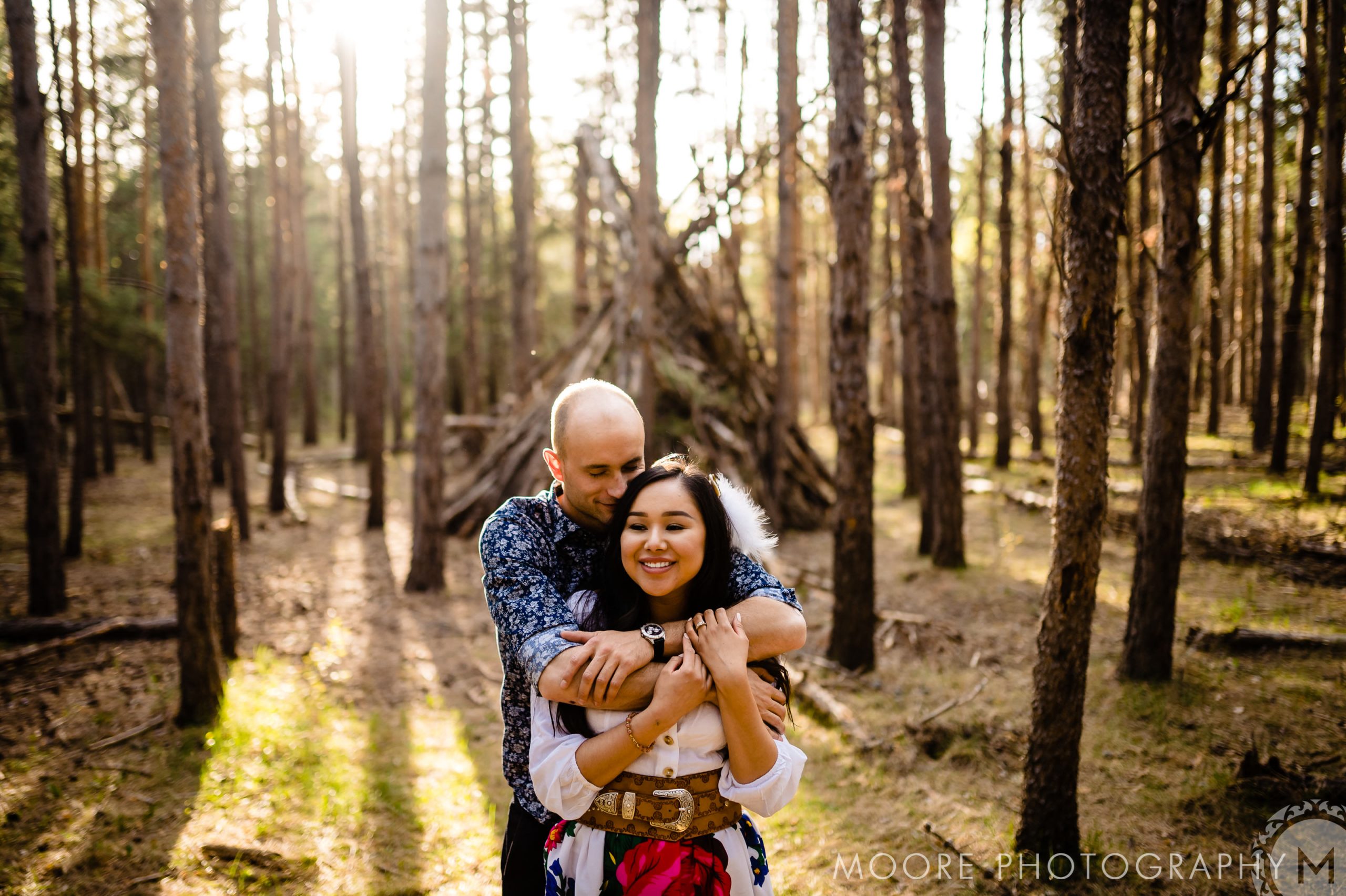 At first nations engaged couple embracing each other in front of trees in a forest in bird Hill park