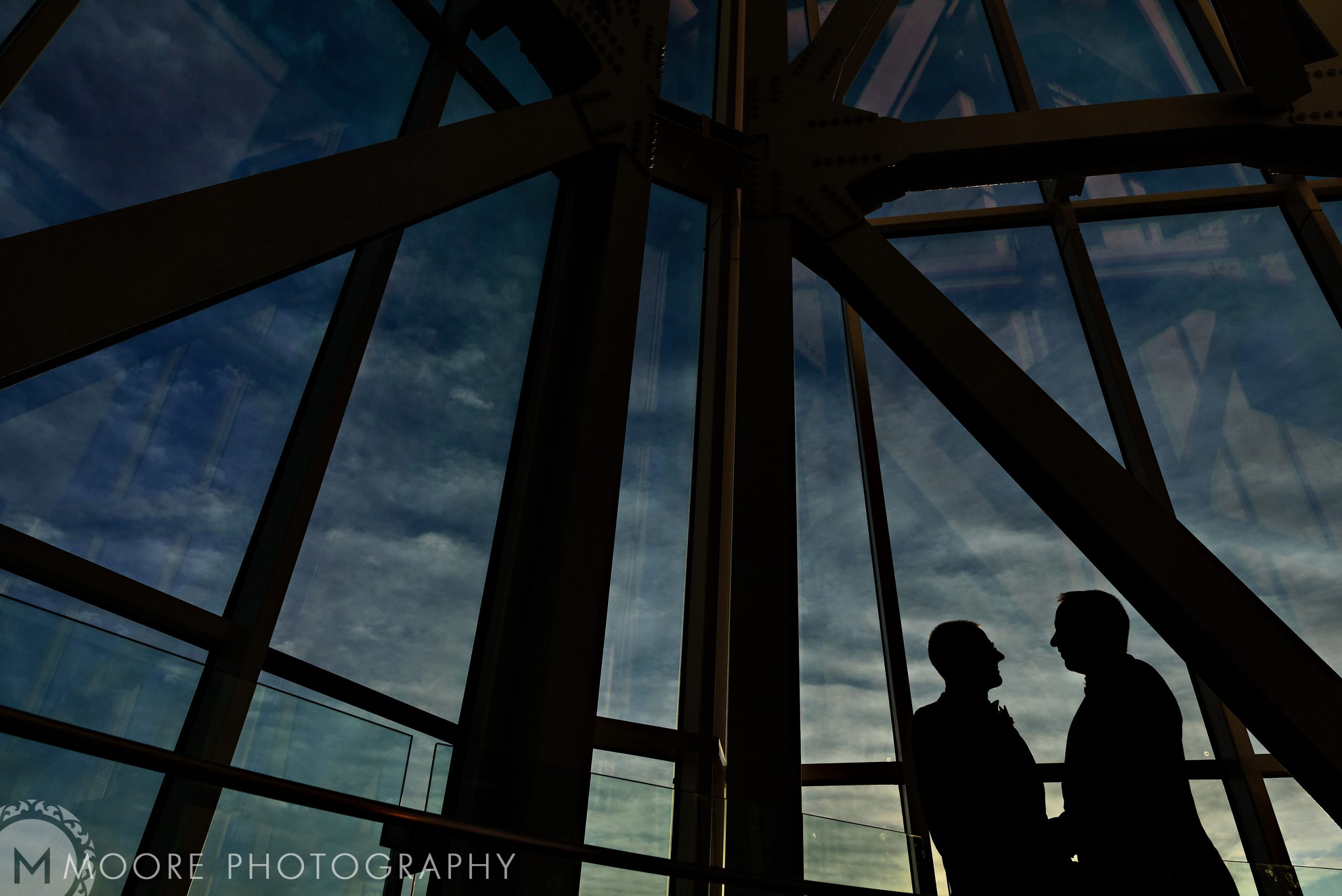 Silhouetted couple at large windows, clouds above; a dreamy Winnipeg wedding venue.