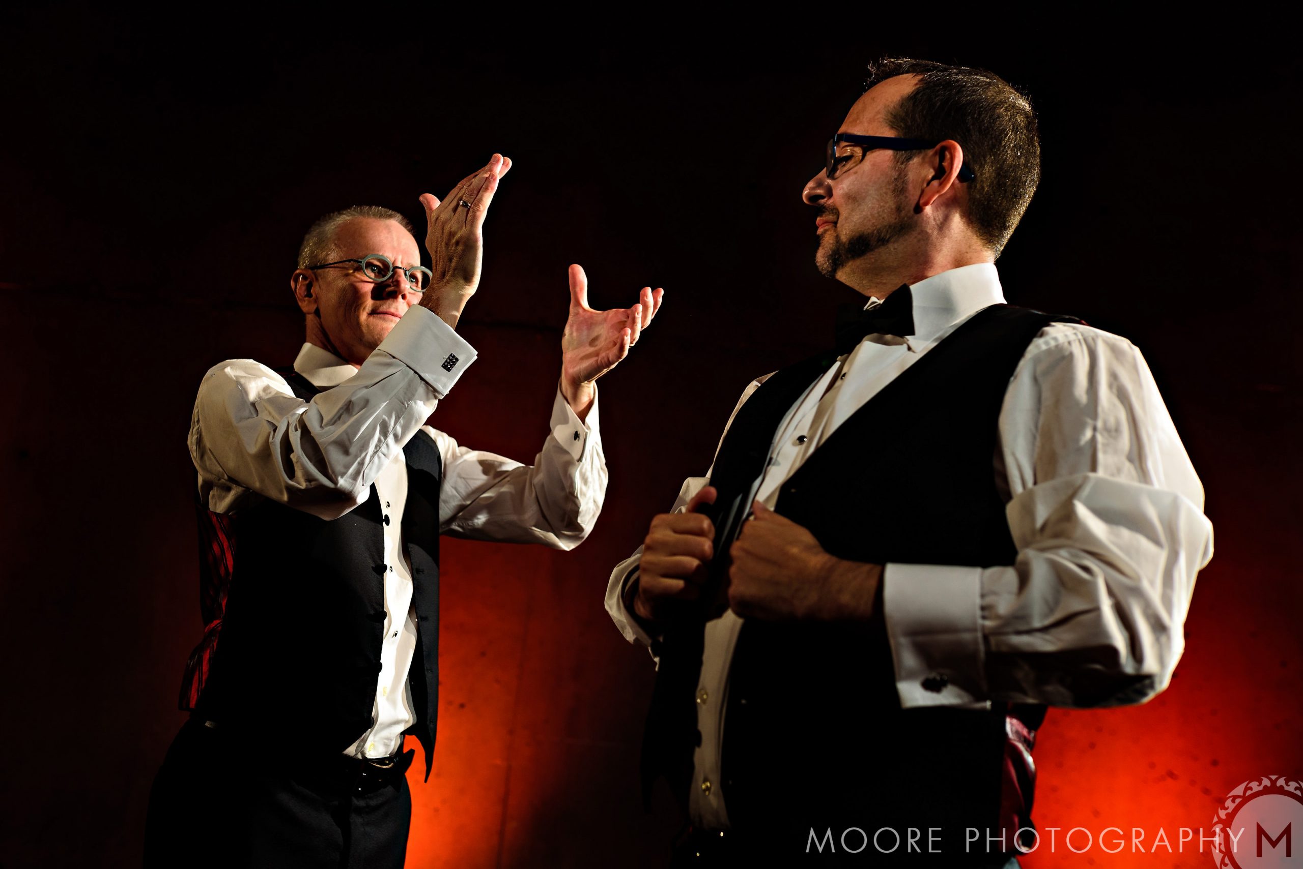 Two men in formal wear, prepping at Winnipeg wedding venues, one adjusting his vest.