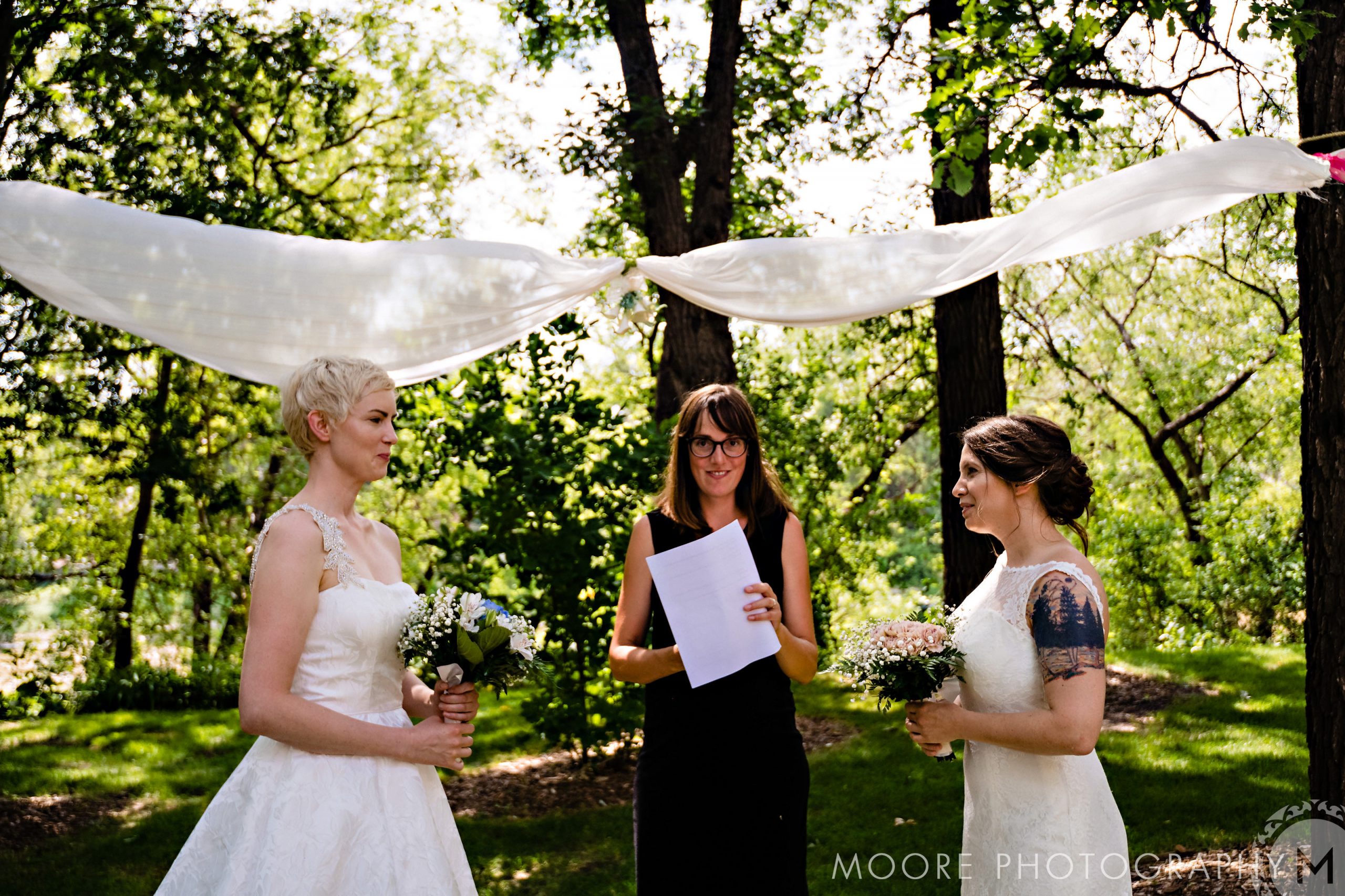 Intimate outdoor wedding with two brides under a canopy at Winnipeg wedding venues.