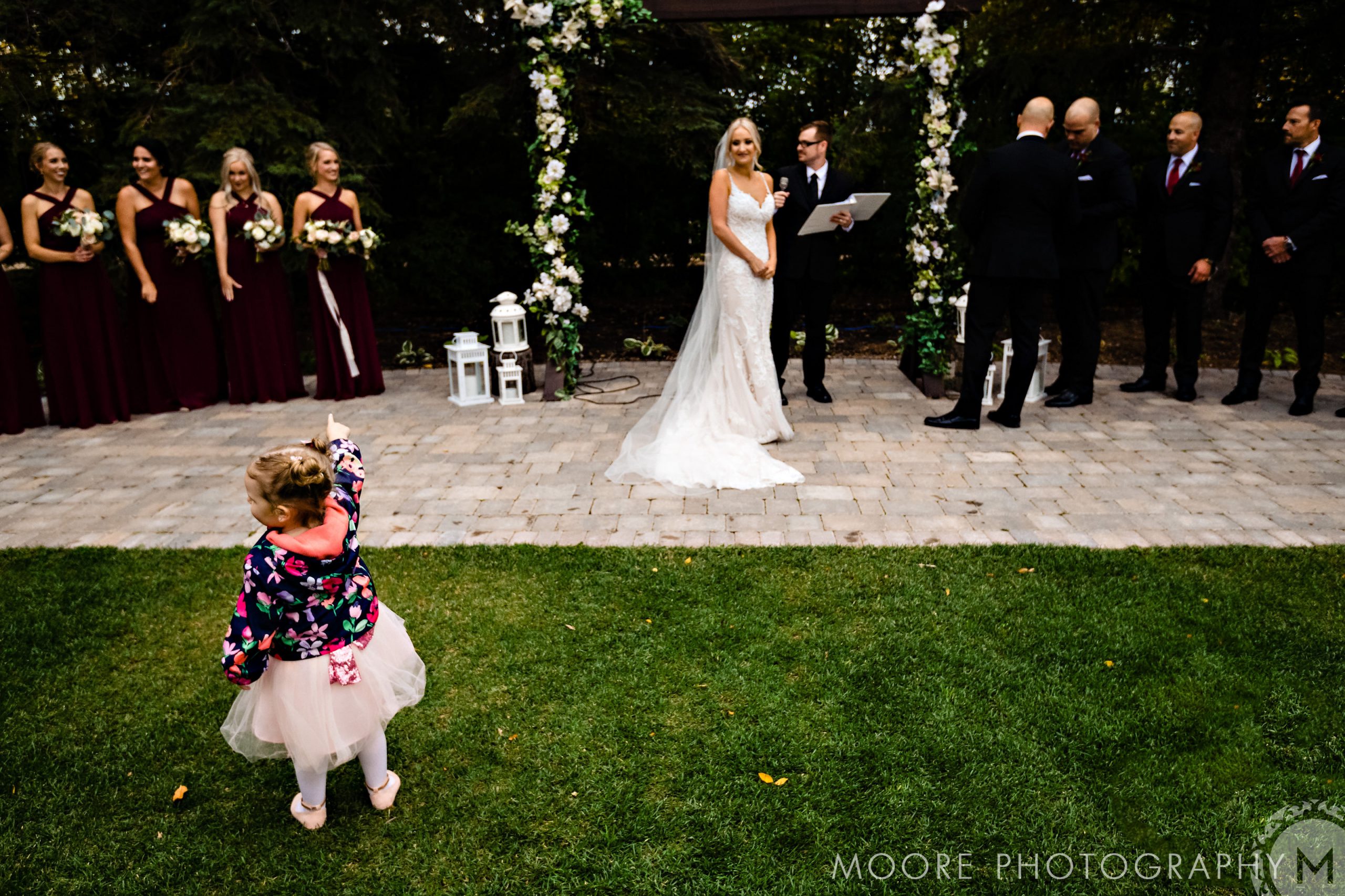 Little girl pointing at a bride during an outdoor ceremony at Winnipeg wedding venues.