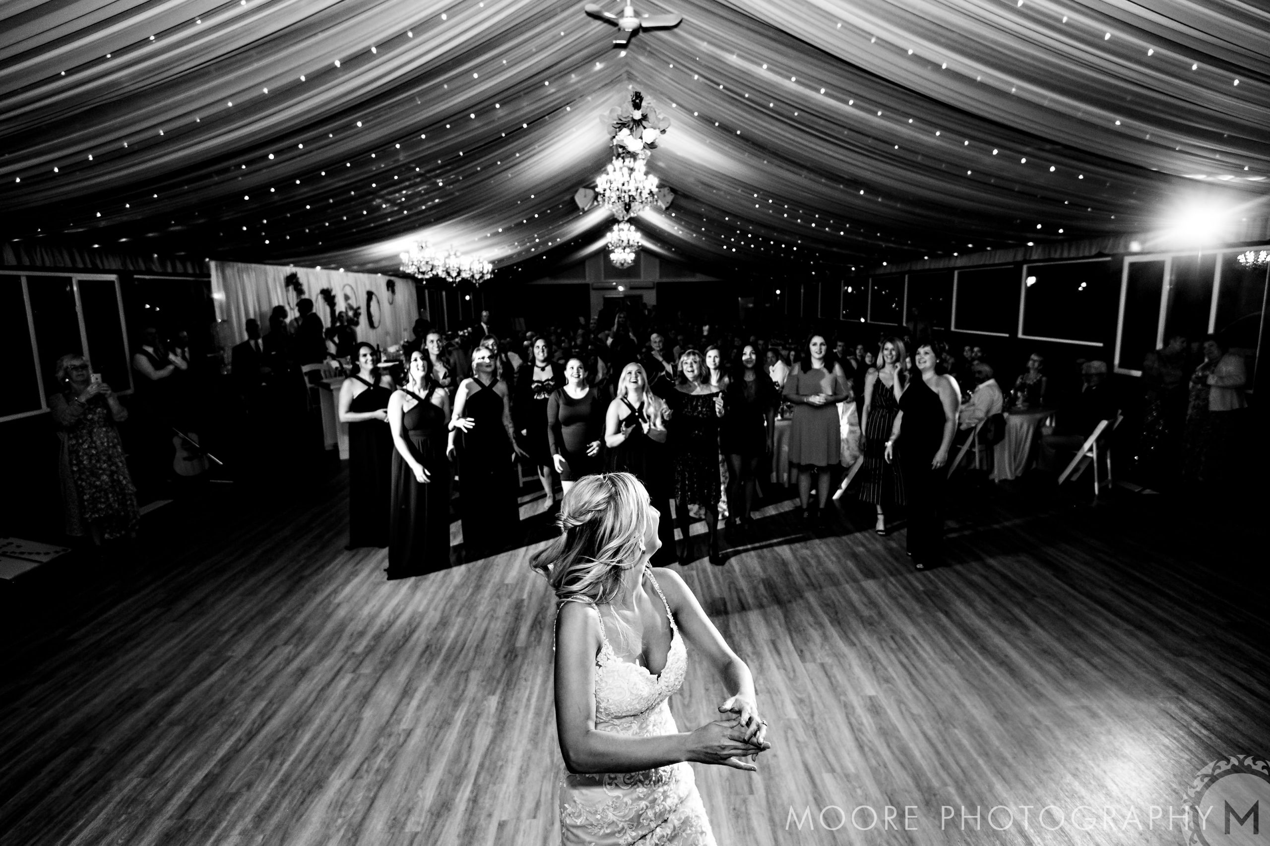 Bride tossing bouquet at guests in a beautifully adorned Winnipeg wedding venue.