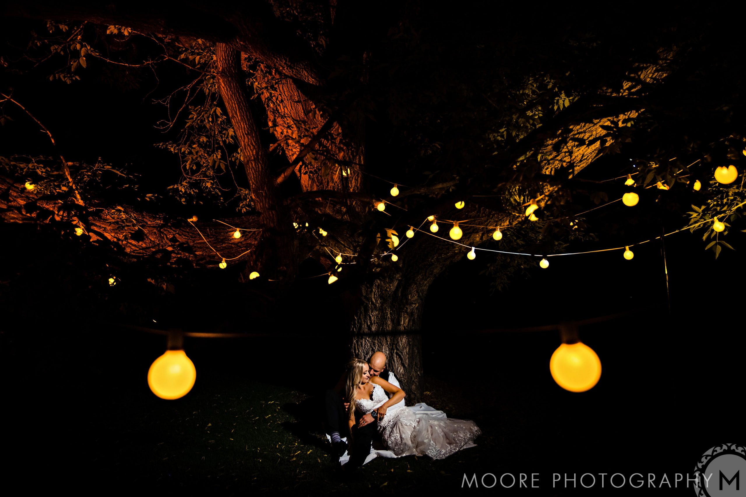 A couple embraces under lit trees at a Winnipeg wedding venue.