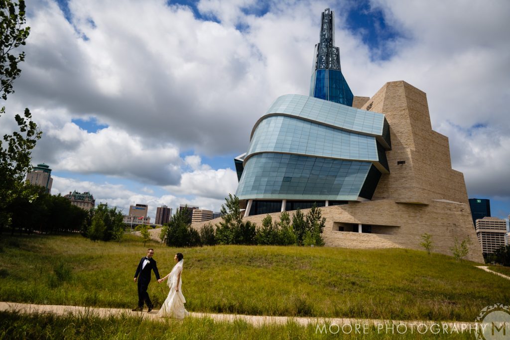 Couple in formal attire strolling by a modern building; ideal for Winnipeg wedding venues.
