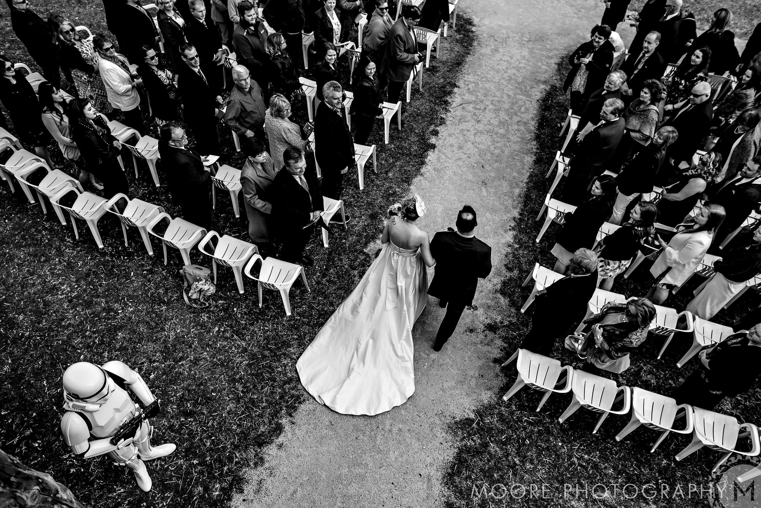 Bride and father walk down the aisle at a Winnipeg wedding venue; a stormtrooper watches.