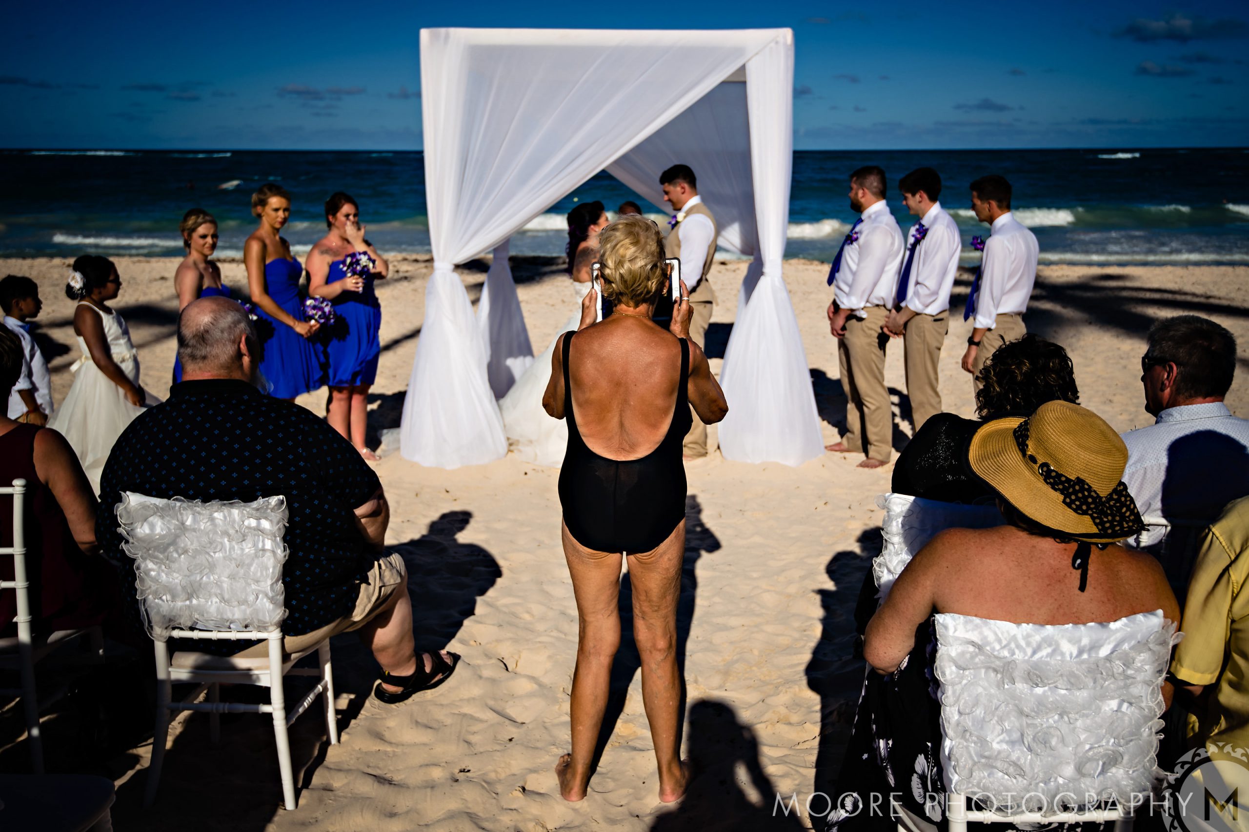 old lady in a bikini photobombing a destination wedding with her ipad