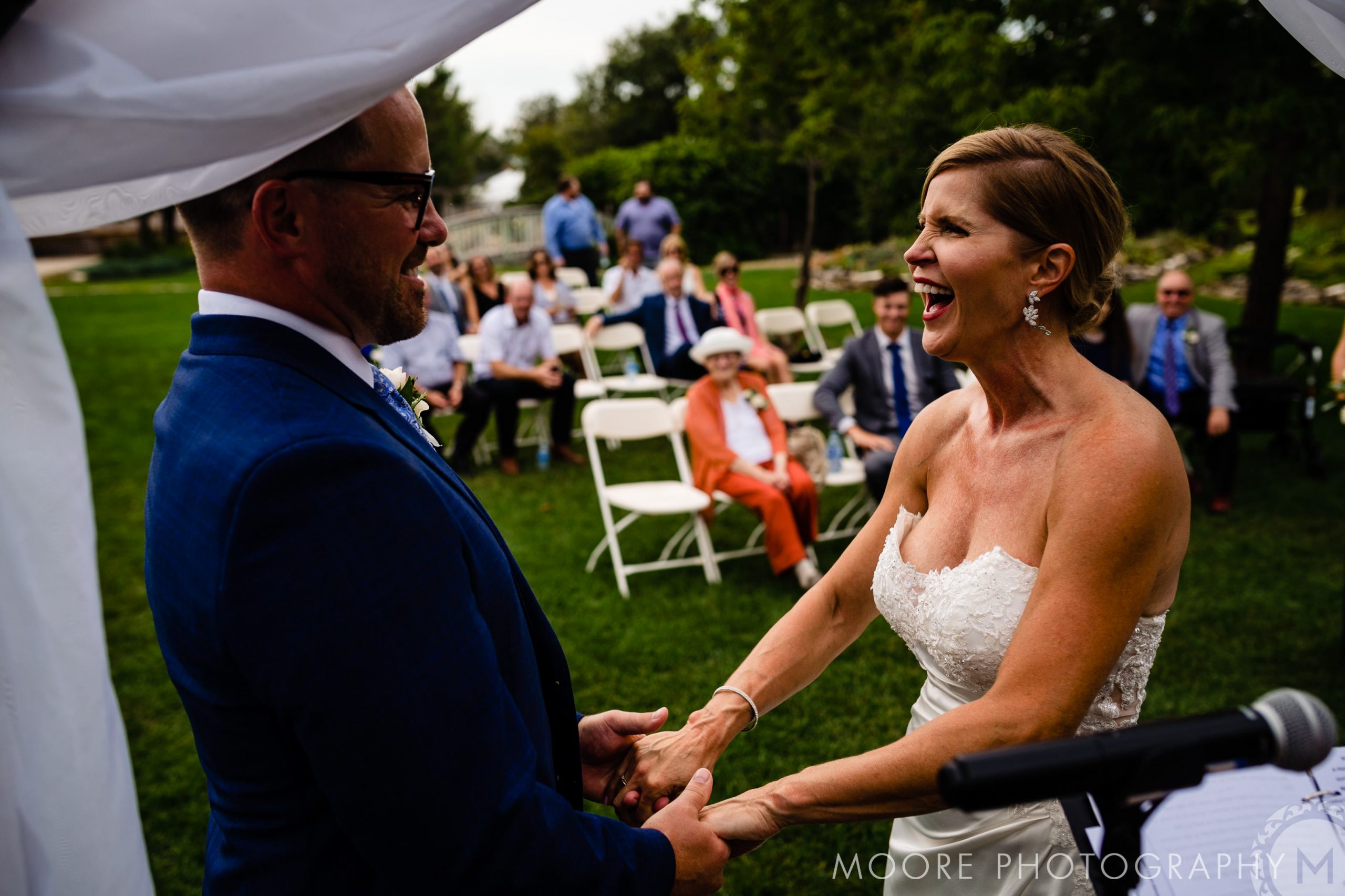 Bride and groom laughing, holding hands at Winnipeg wedding venues ceremony.