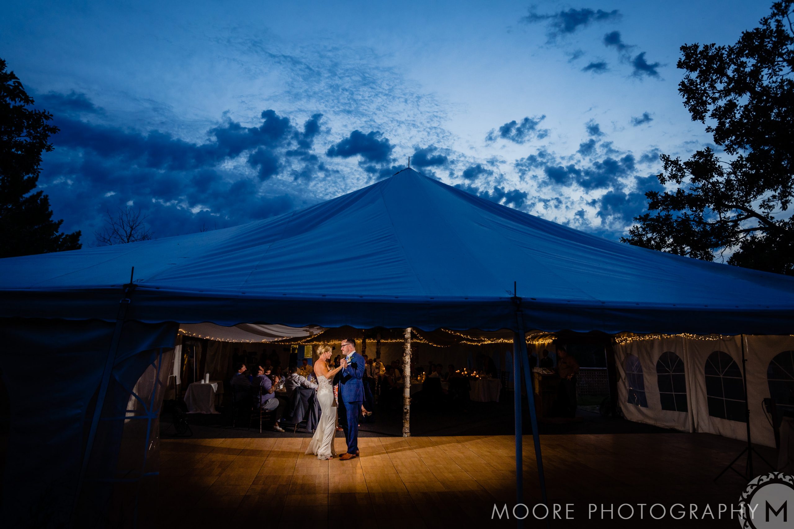 A couple dances under a lit tent at dusk, perfect for Winnipeg wedding venues.