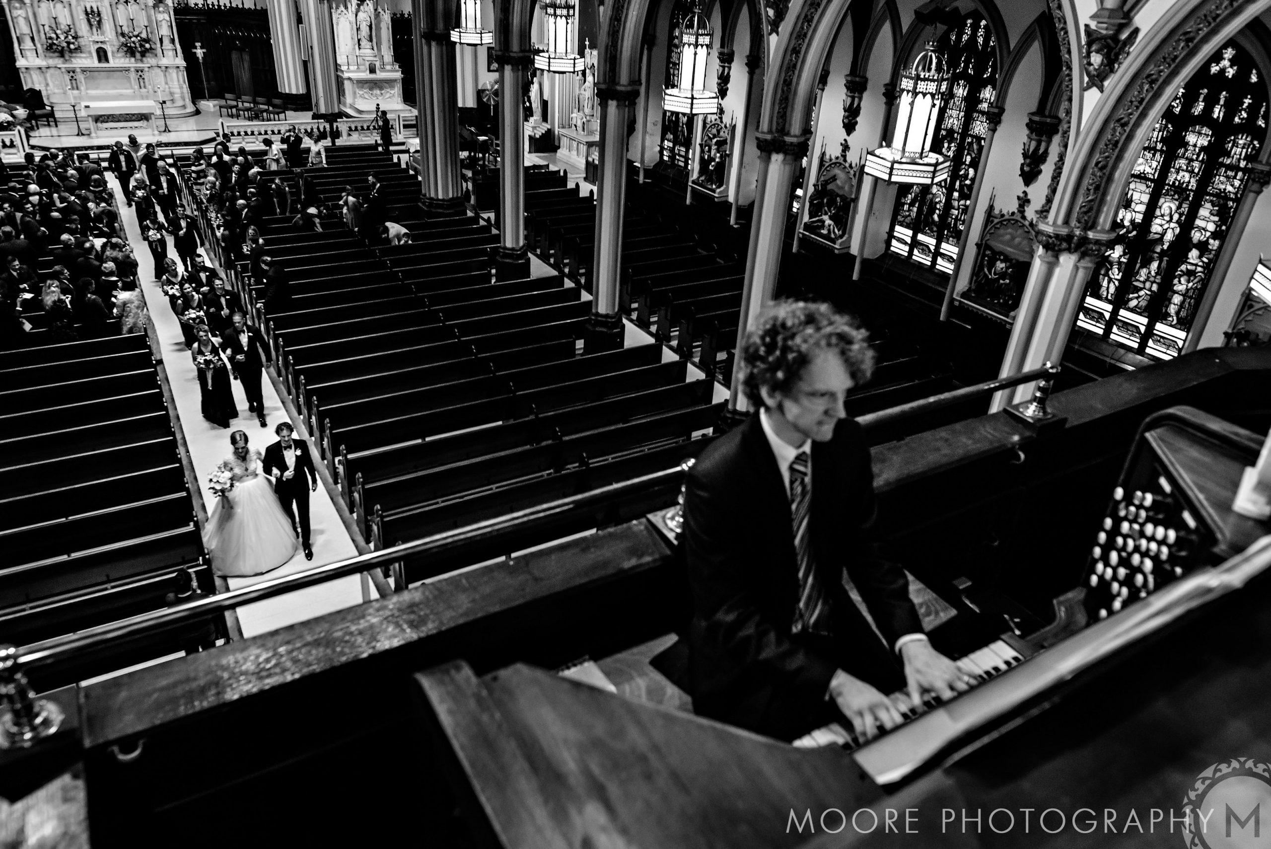 Person plays organ above New York City destination wedding in church balcony.