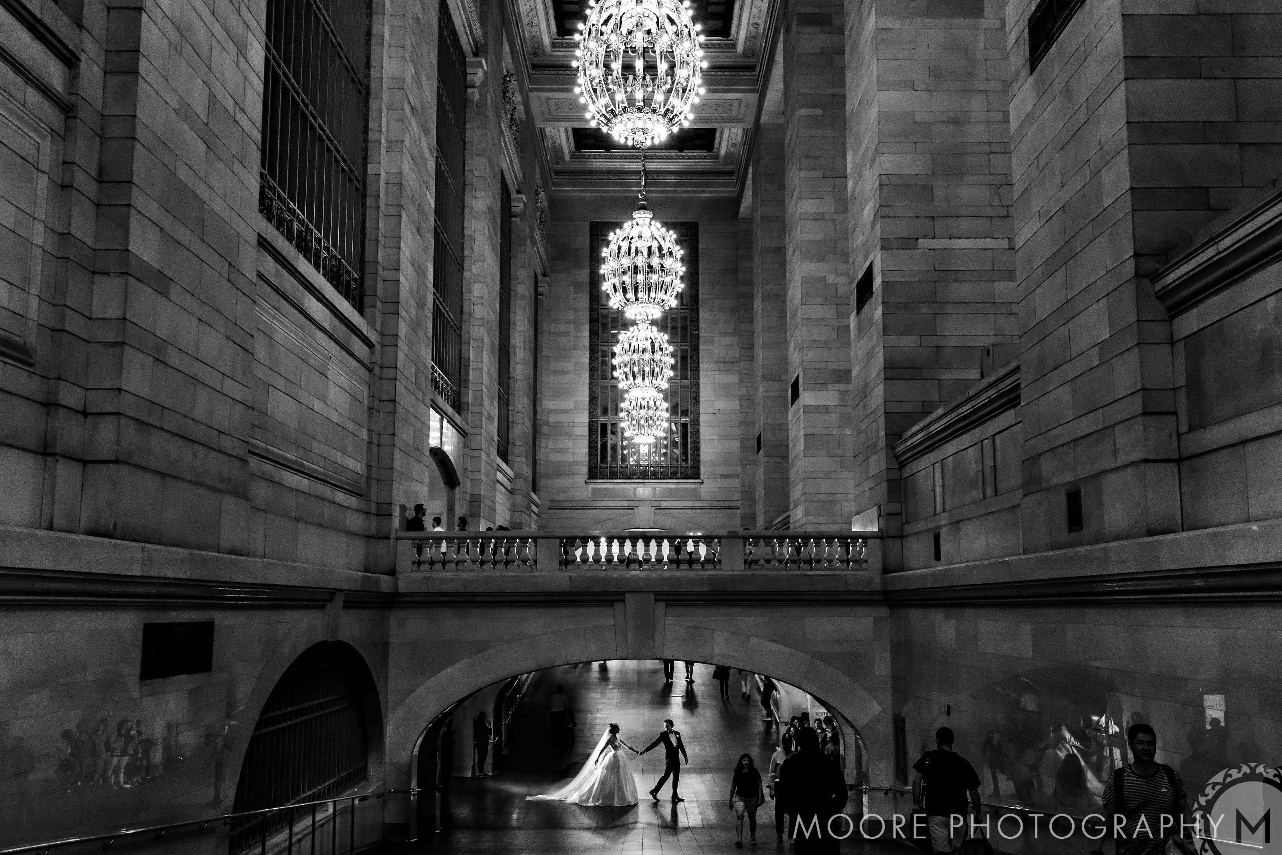 Under chandeliers, a couple dances in New York City's grand train station hall at night.