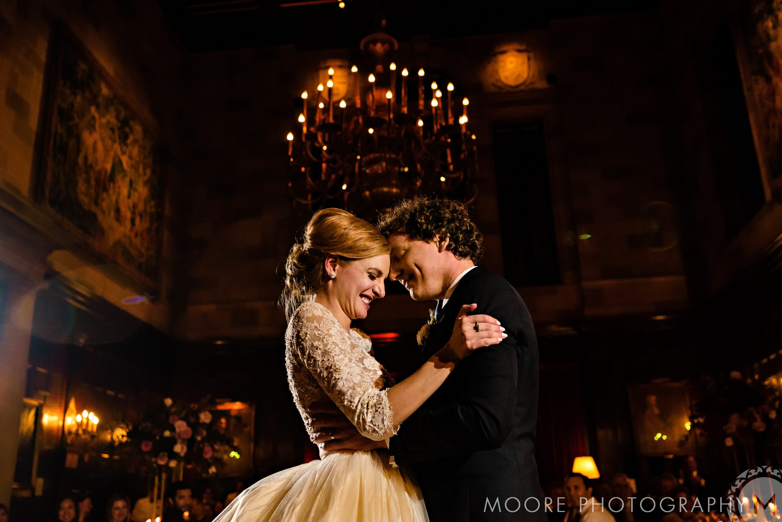Bride and groom embrace during their first dance in a dimly lit New York City venue.