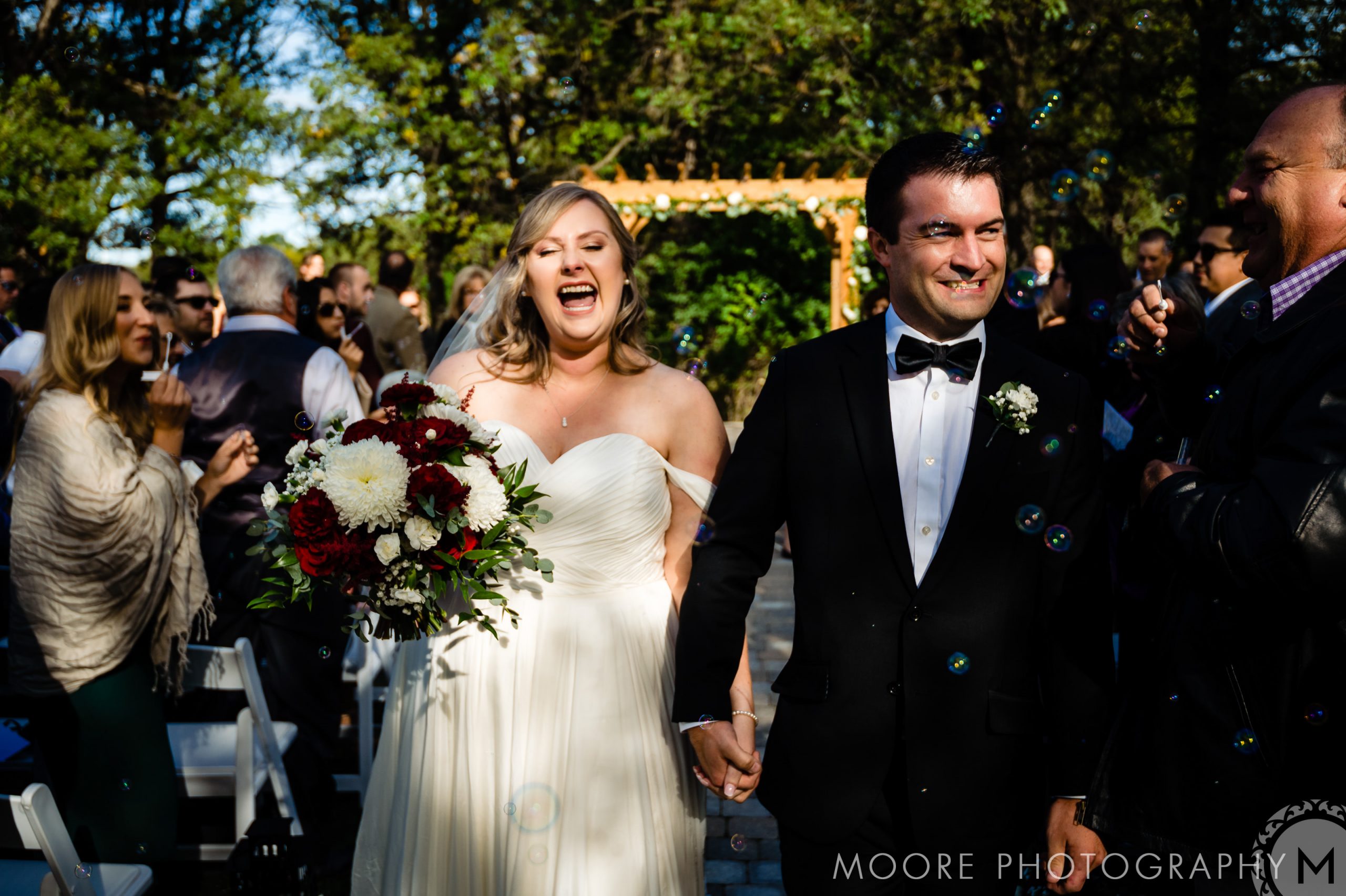 Bride and groom smiling, holding hands at a Winnipeg wedding venue ceremony.