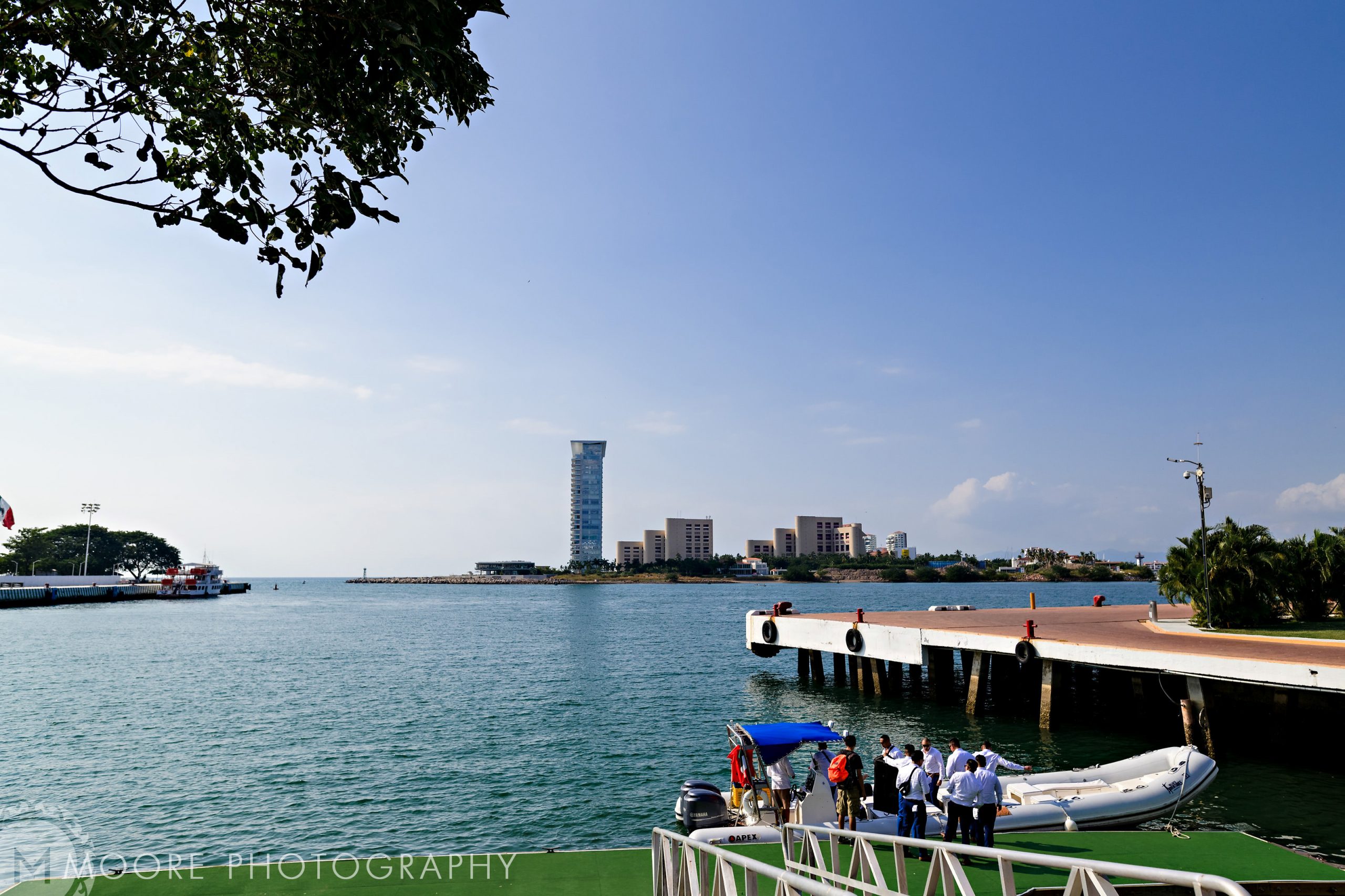 Harbor scene in Puerto Vallarta with docked boat and buildings across the water under clear blue sky.