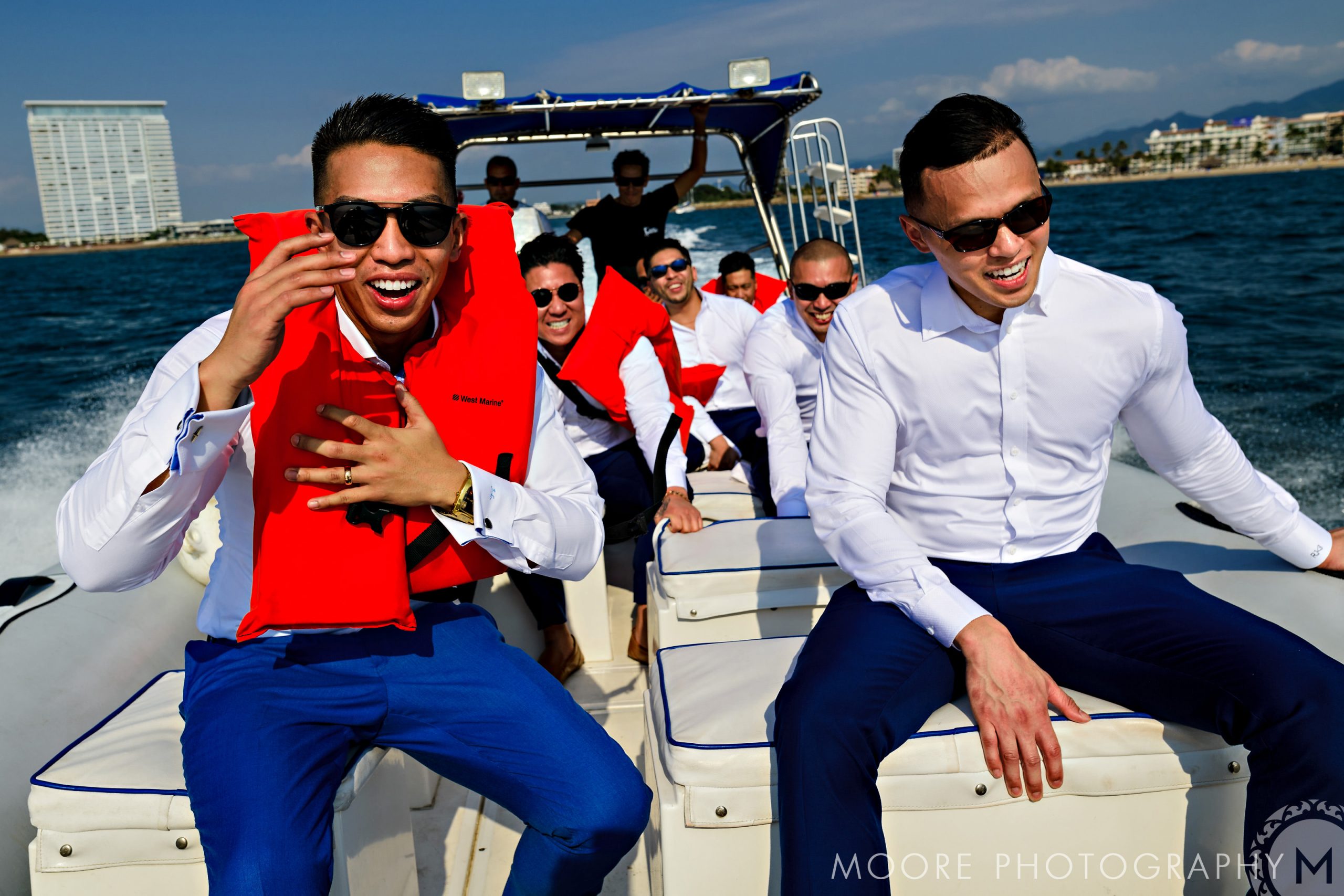 Group of men in formal attire on a boat, enjoying a sunny Puerto Vallarta day.
