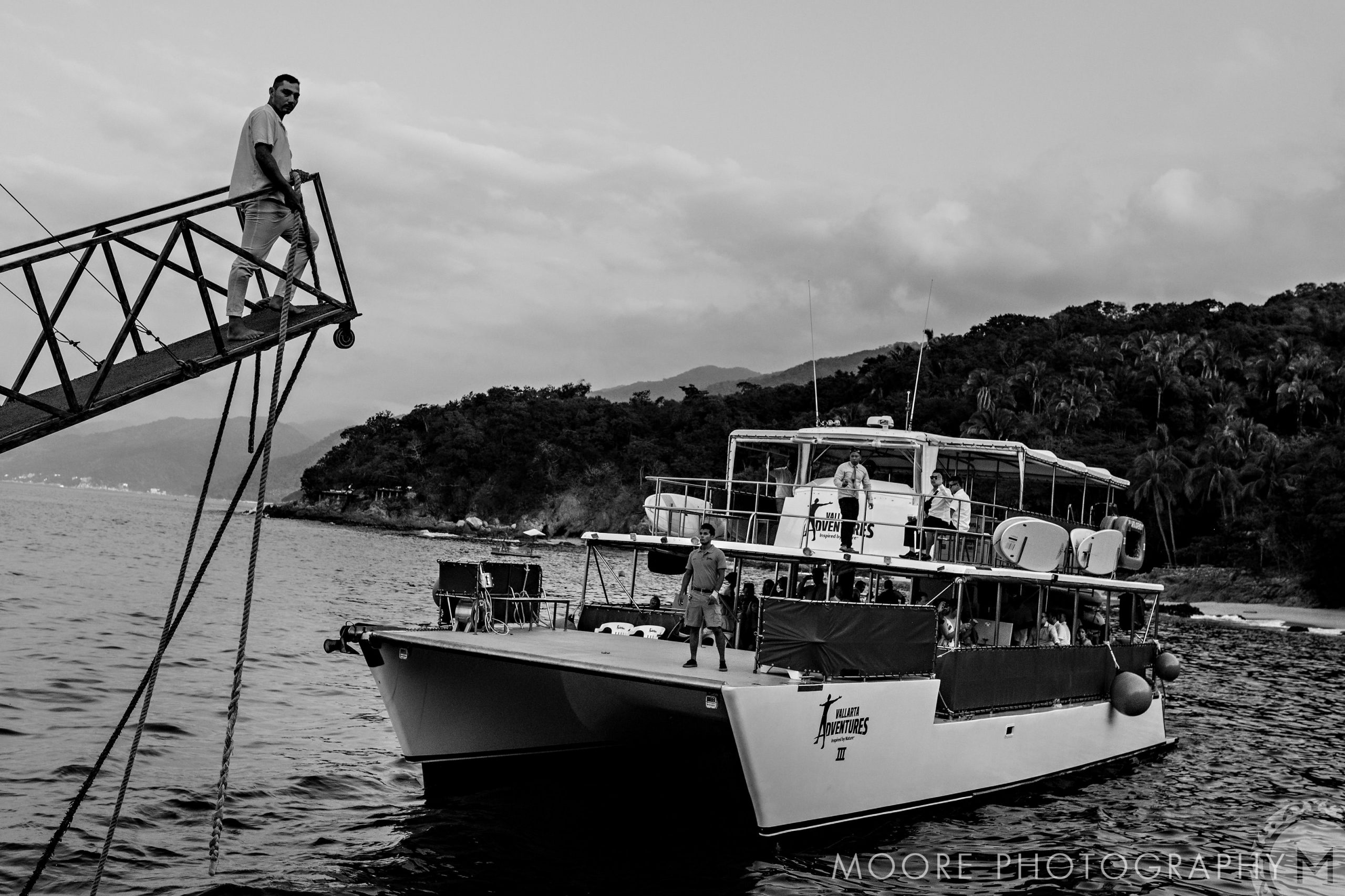 Person on a dock near a wedding boat, over water, hills in Puerto Vallarta backdrop.