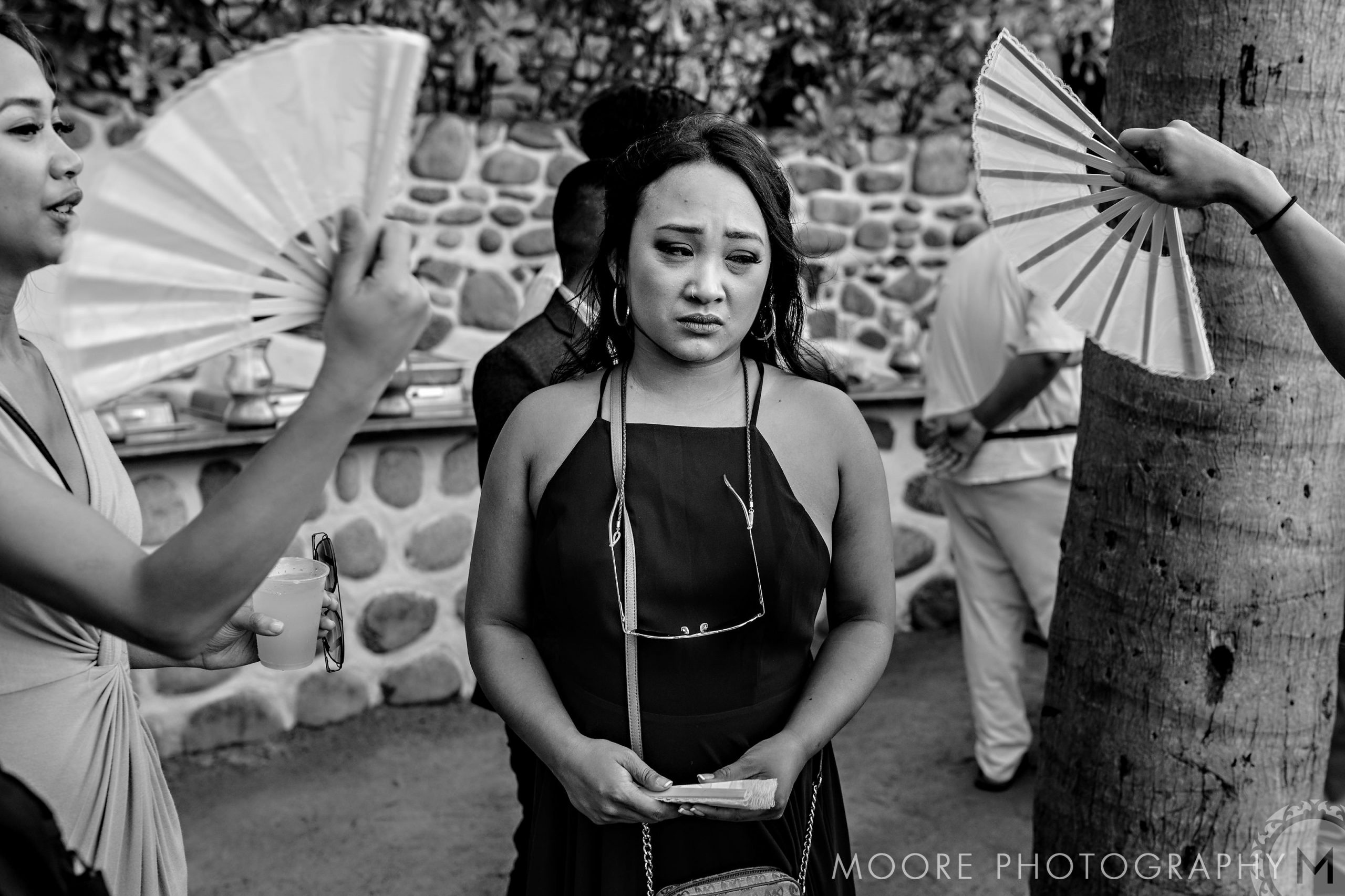At a Puerto Vallarta wedding, a woman in a dark dress looks concerned as others fan her.
