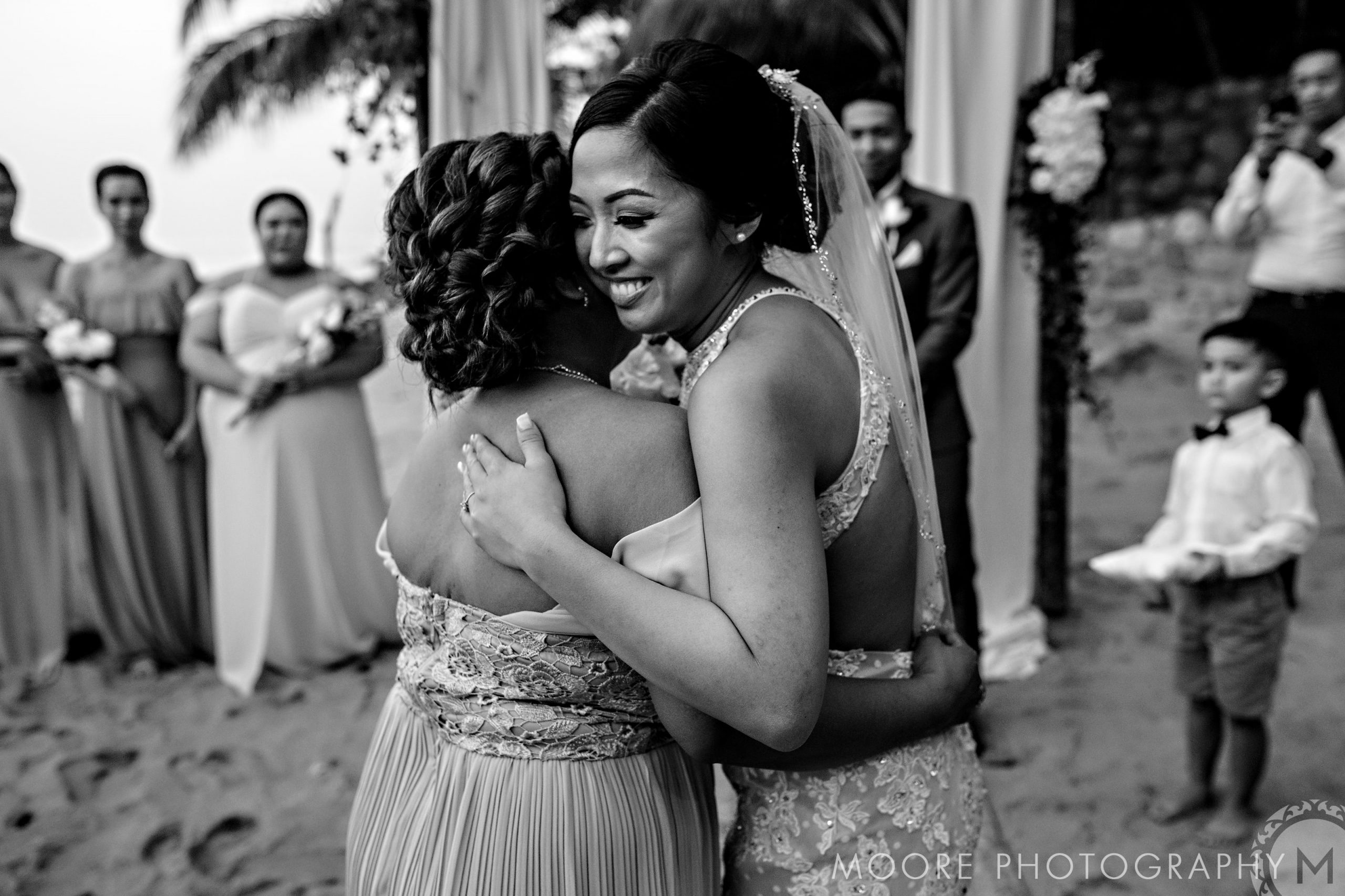 Bride and bridesmaid hug at a Puerto Vallarta destination beach wedding.
