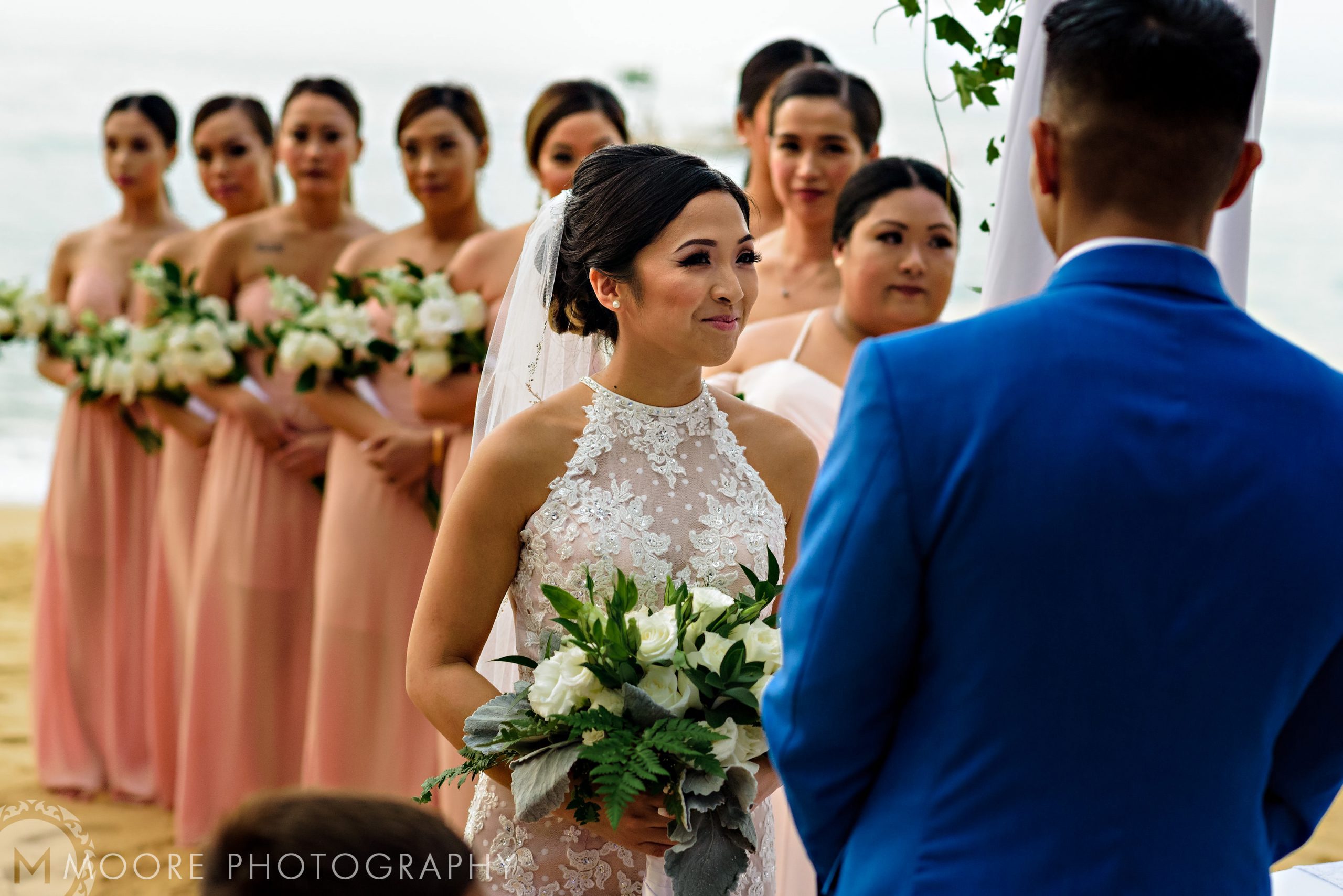 Bride and groom at a Puerto Vallarta beach wedding, with bridesmaids in peach dresses.