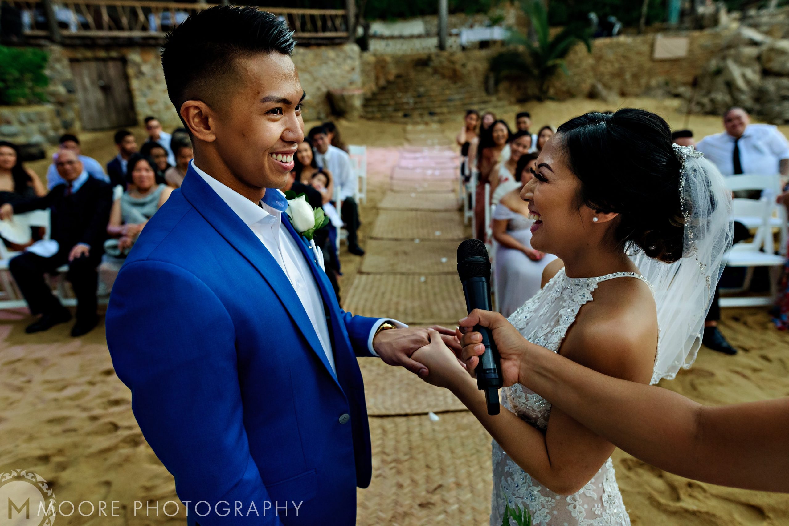 Couple smiling at a Puerto Vallarta destination wedding, holding hands and sharing a microphone.