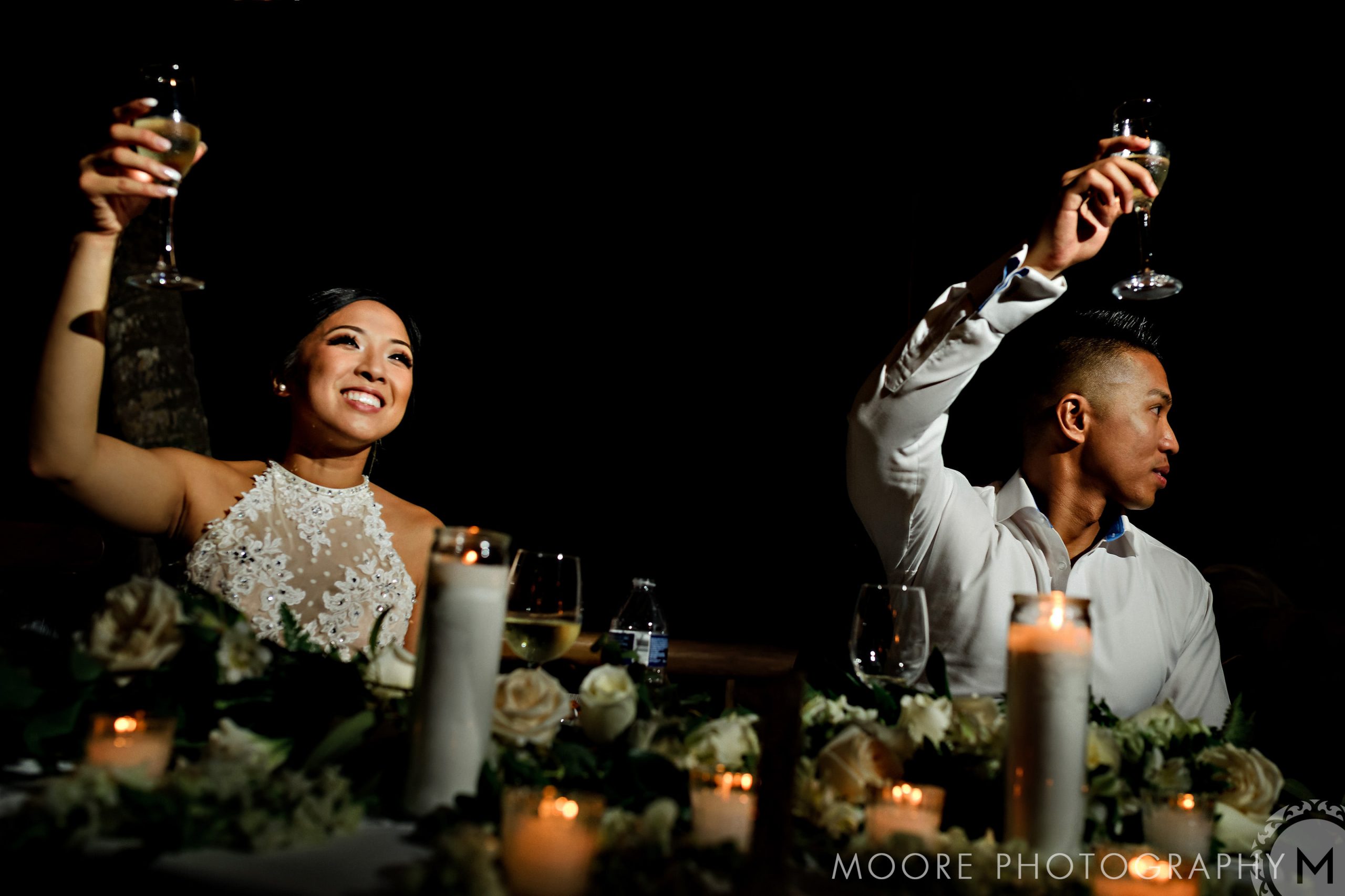 Couple at a Puerto Vallarta wedding toasting amid flowers and candles with champagne.