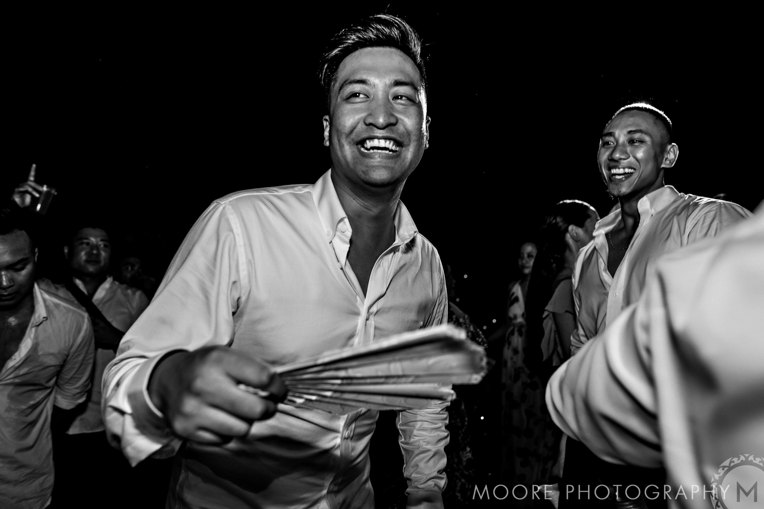 A man joyfully holding a fan, dancing at a Puerto Vallarta destination wedding.