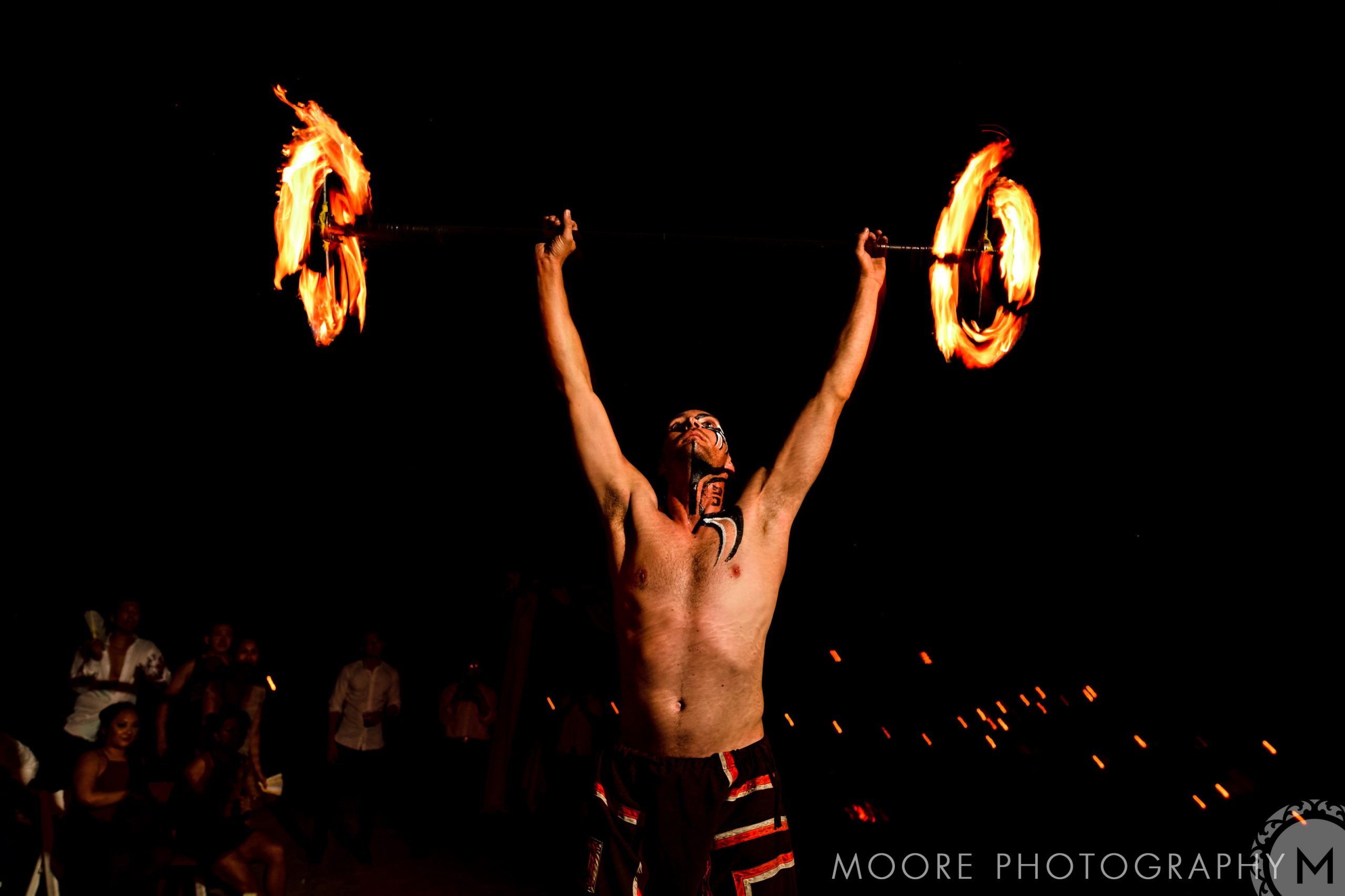 Man performing fire dance with flaming staff at a Puerto Vallarta destination wedding.