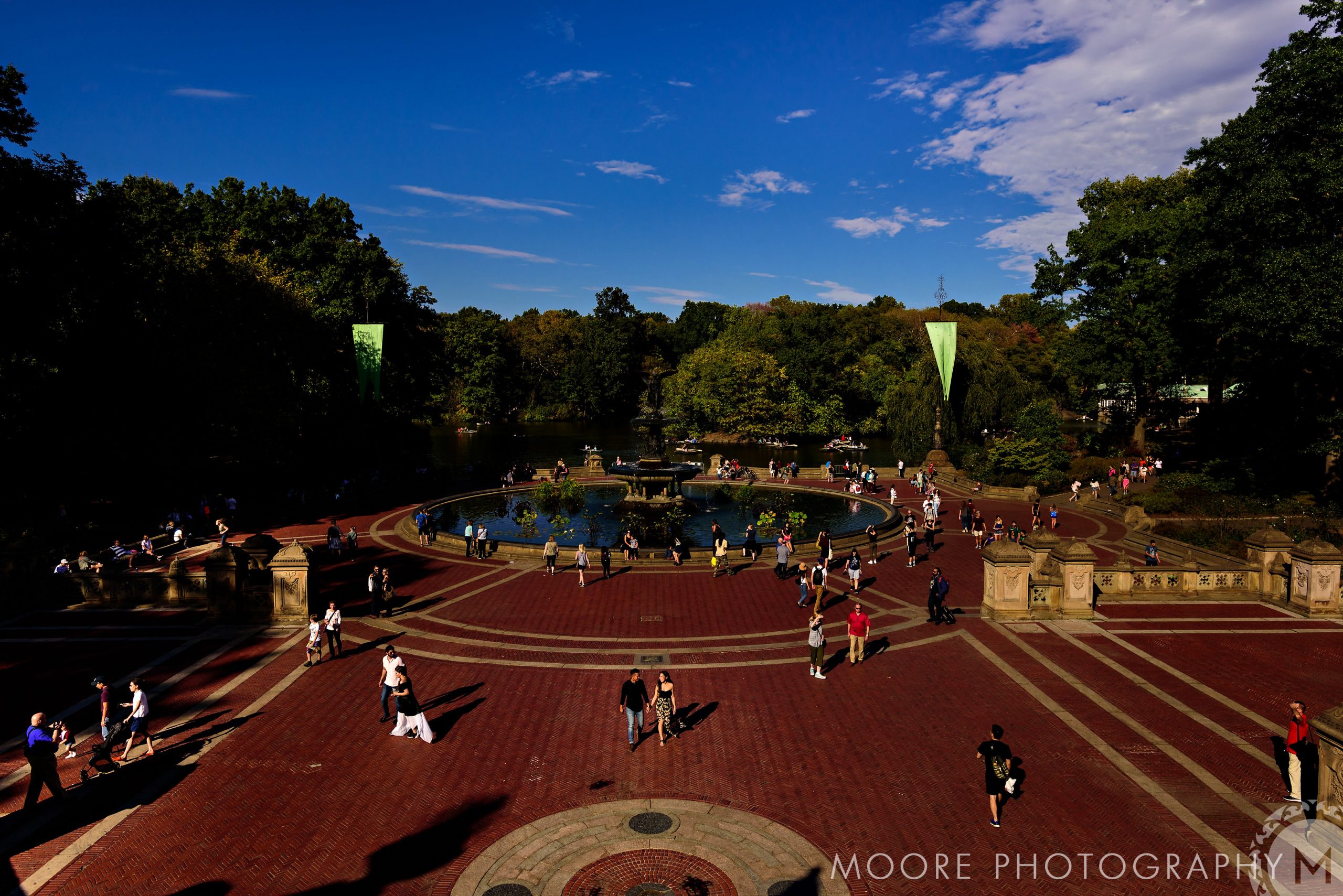 Couple posing for romantic engagement photos around a plaza's central fountain.