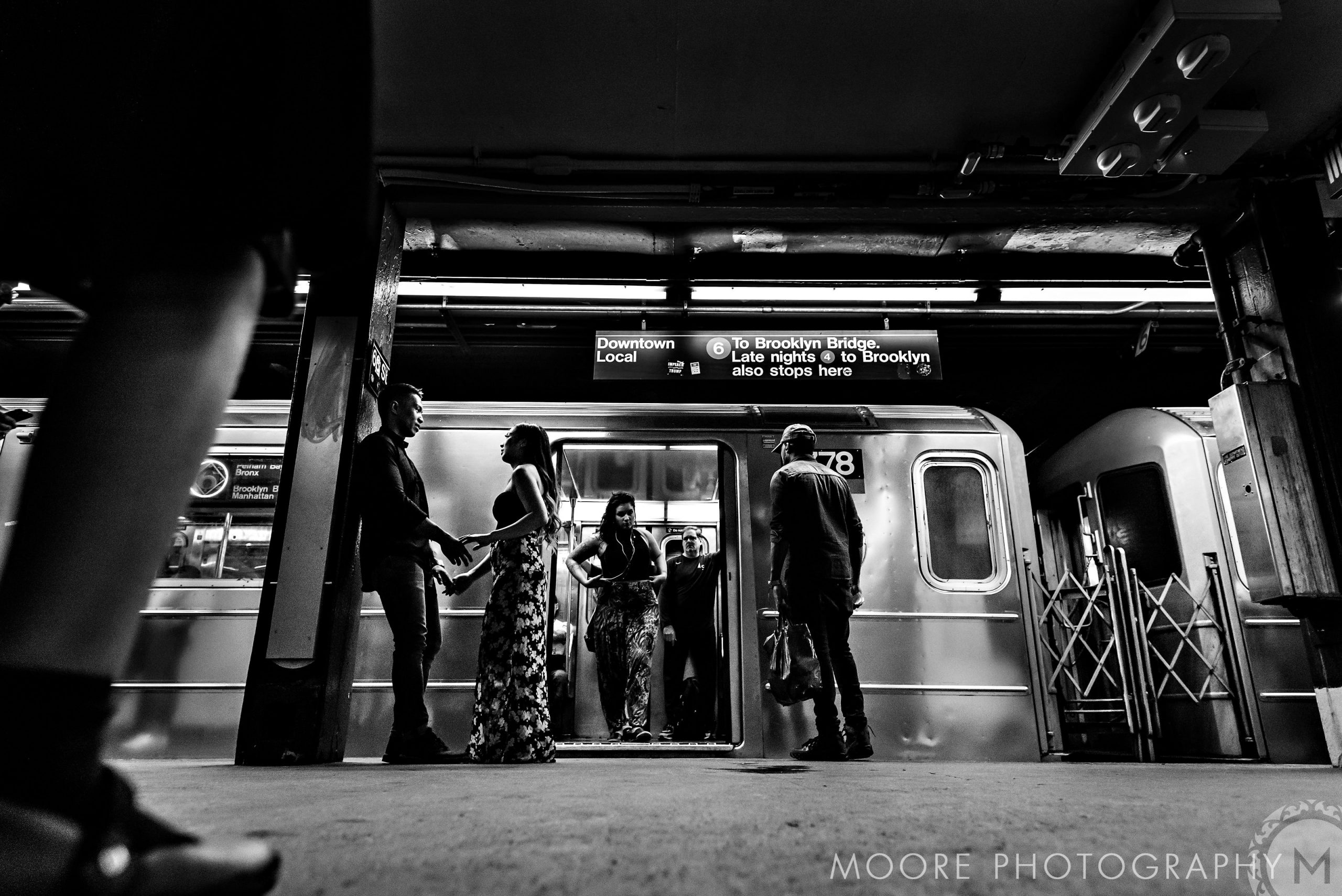Romantic black and white photo of people near a subway train platform.