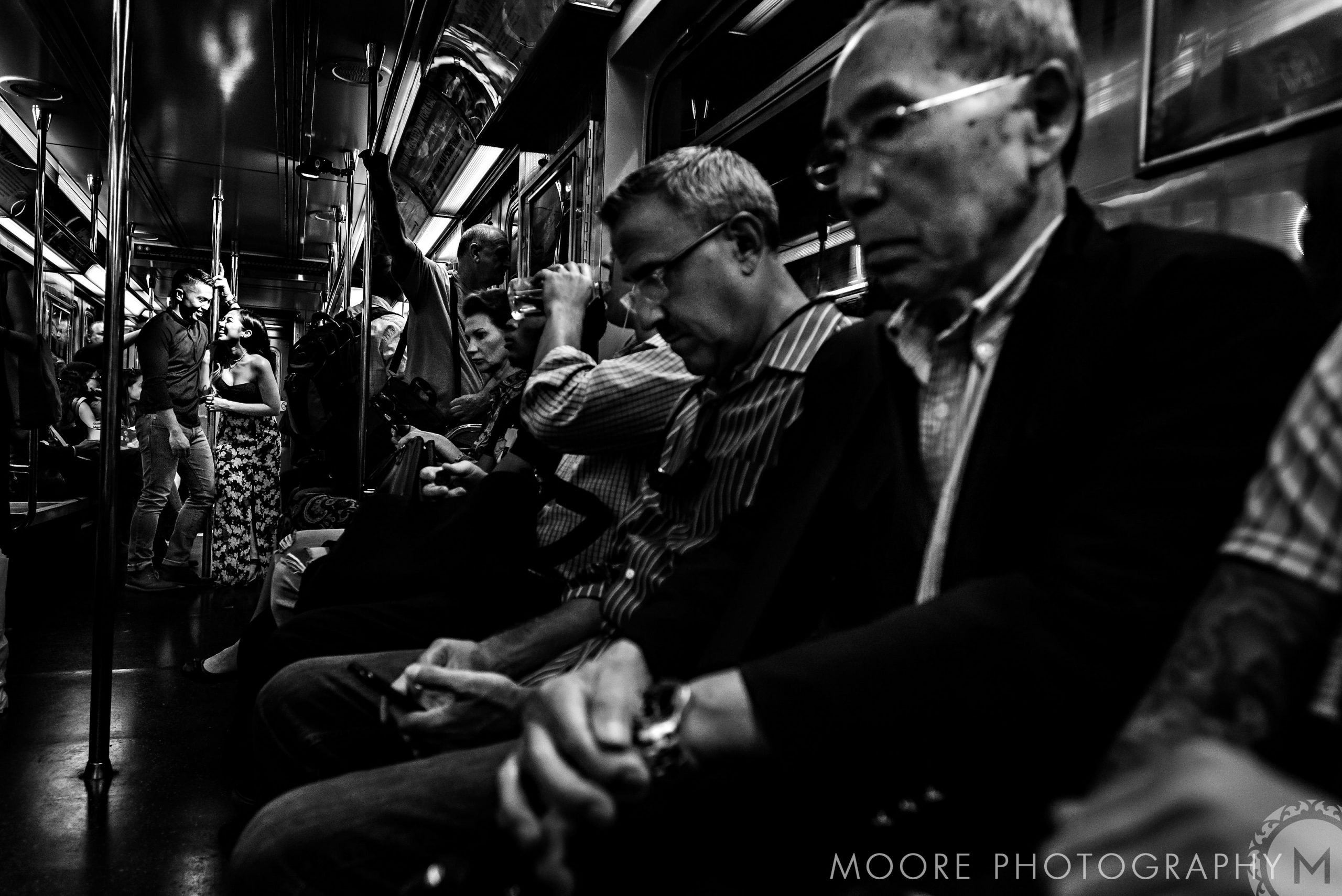 Passengers cozying up on a dimly lit NYC subway train.