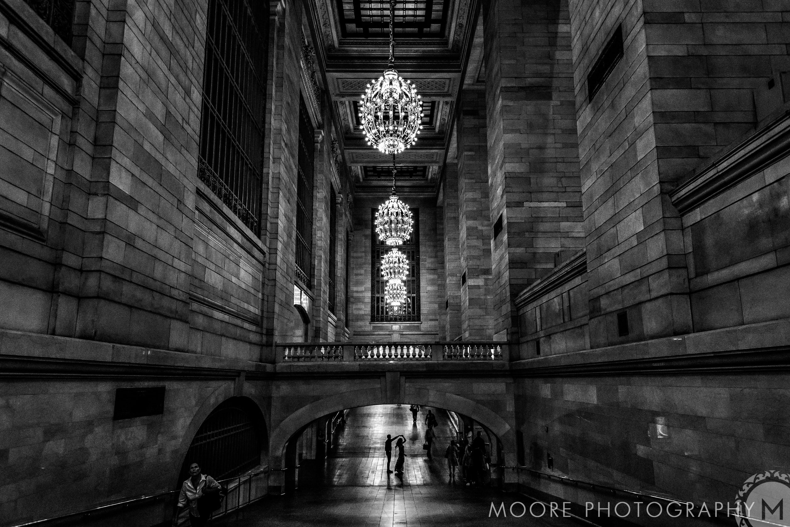 Romantic black and white hallway with chandeliers and a couple in the distance.